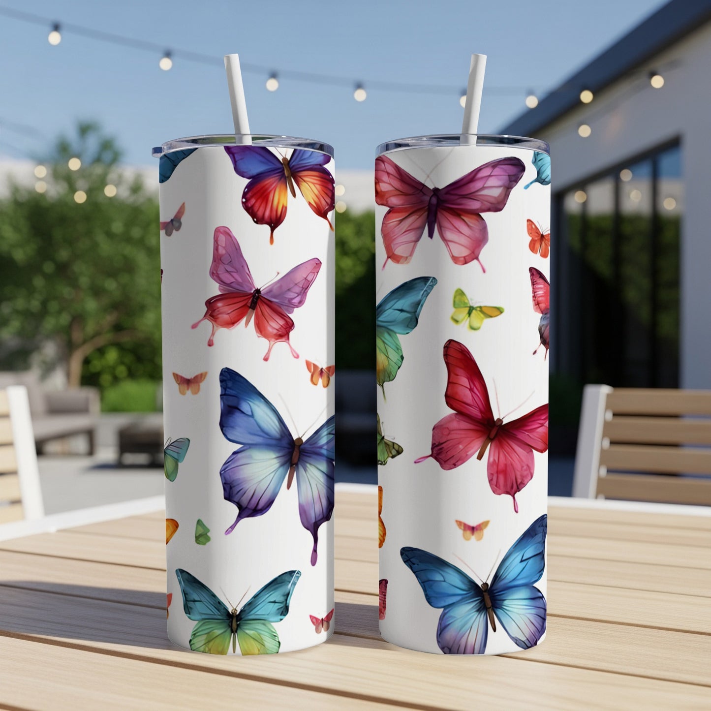 Two white tumblers with colorful butterfly designs on a wooden table.