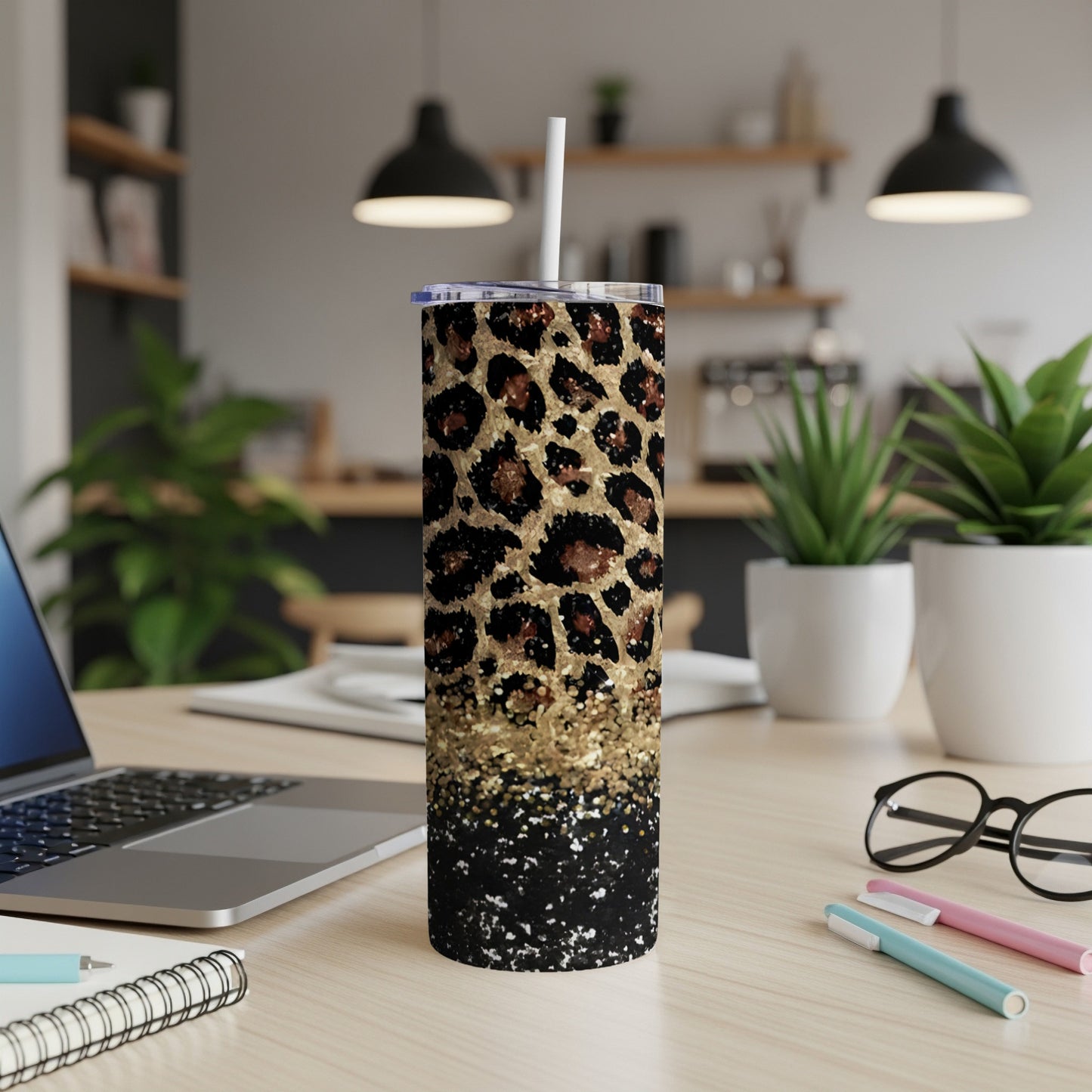 Leopard print skinny tumbler with gold glitter accents on a desk.