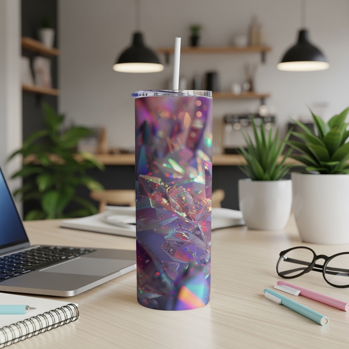 Iridescent tumbler with a straw on a desk with a laptop and pens.