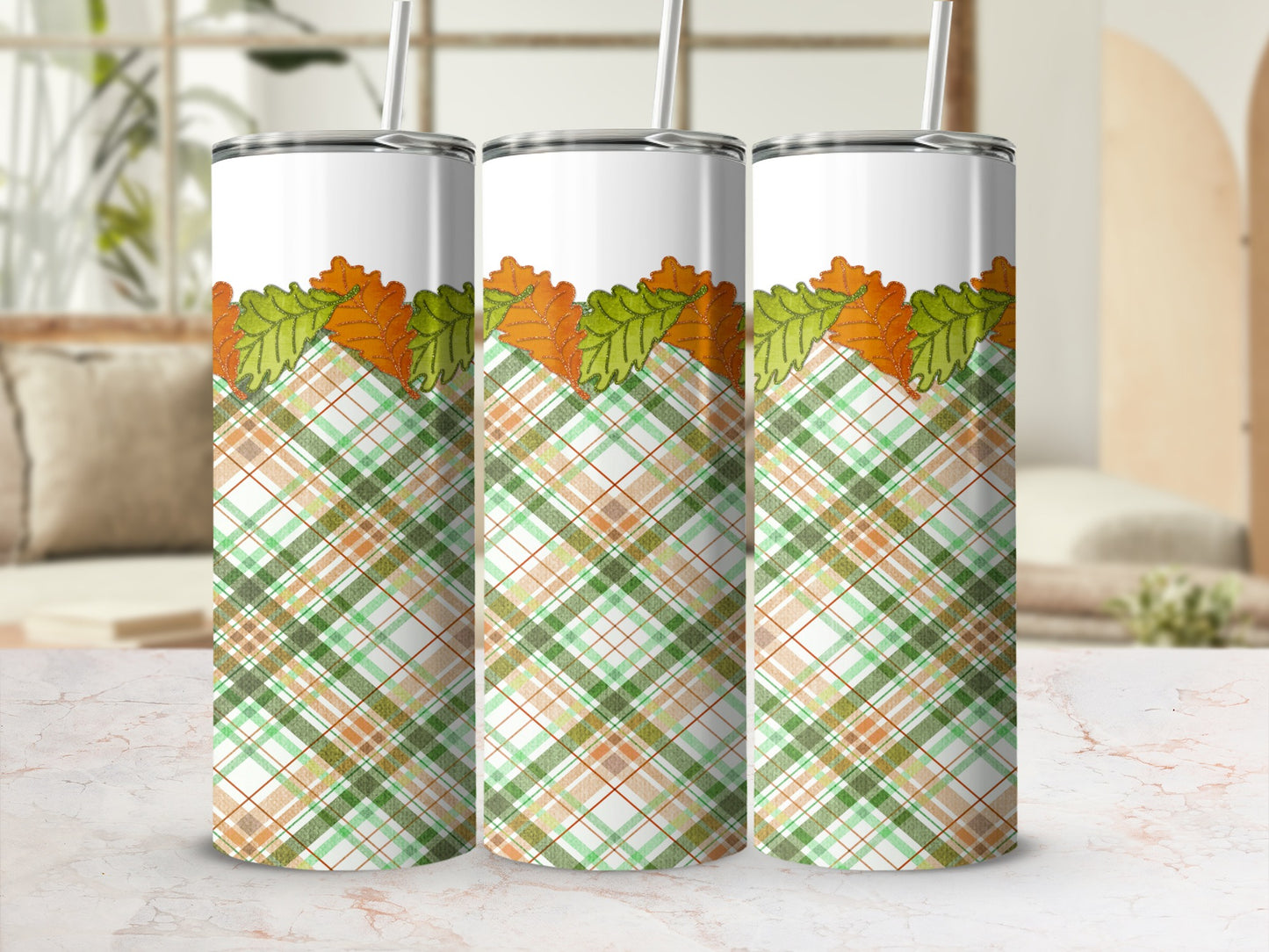 Three tumblers with fall leaves and plaid pattern on a blurred background.