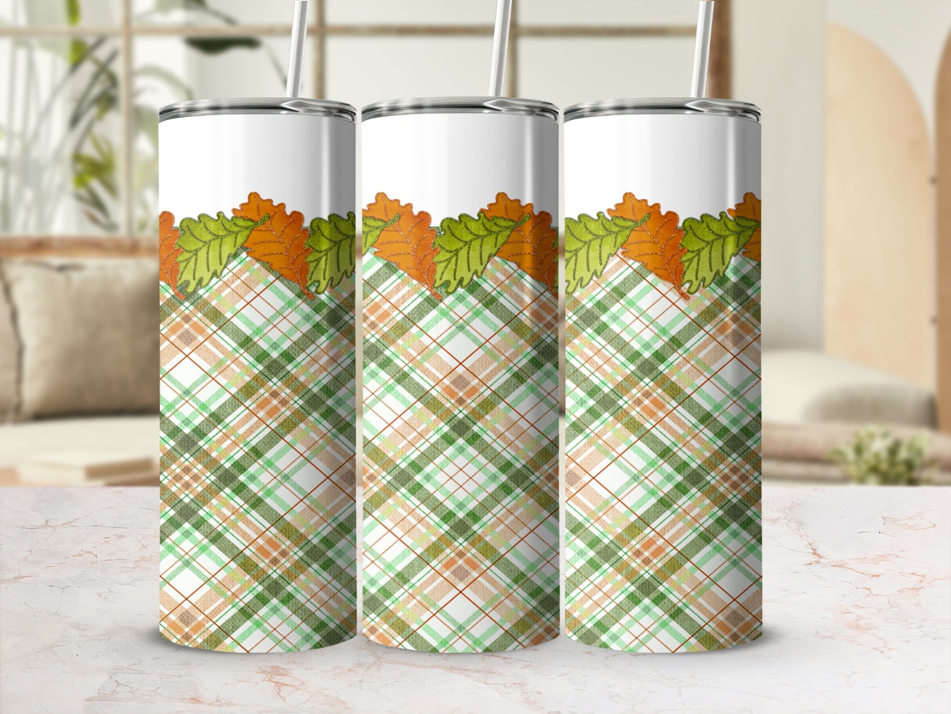 Three tumblers with fall leaves and plaid pattern on a blurred background.