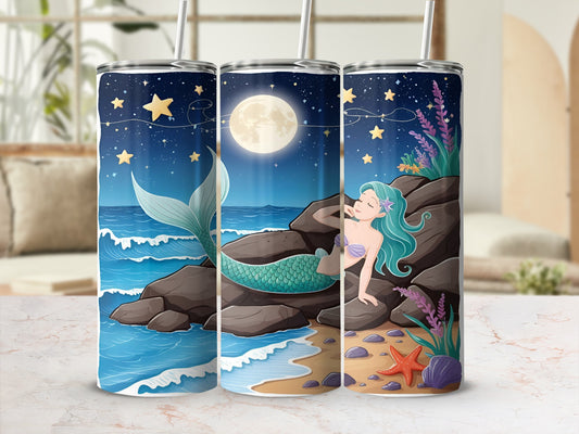 Tumbler with a mermaid on a rocky shore under a starry night sky.