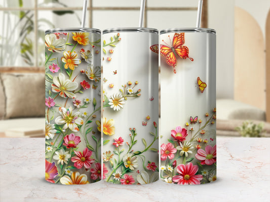Three tall tumblers with vibrant floral and butterfly designs, one with an orange butterfly.