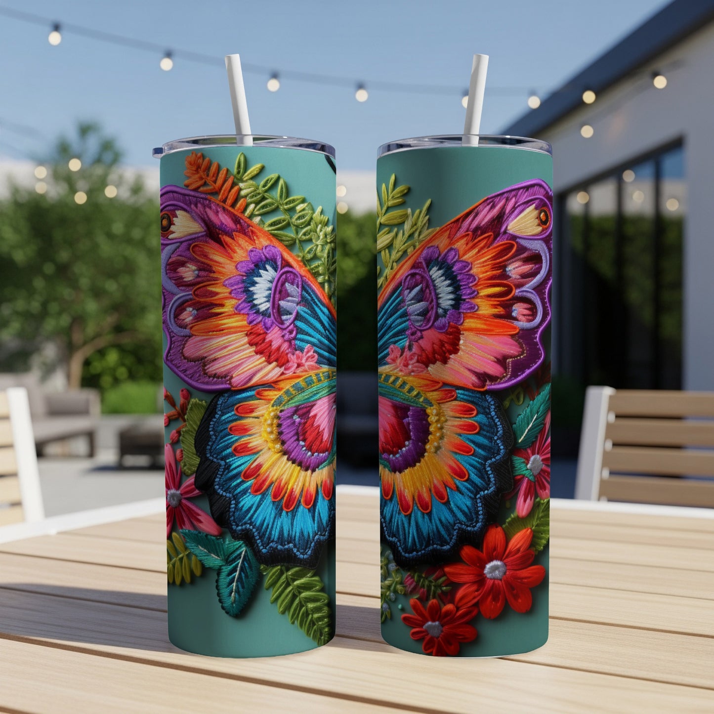 Two teal tumblers with colorful embroidered butterfly and floral designs.