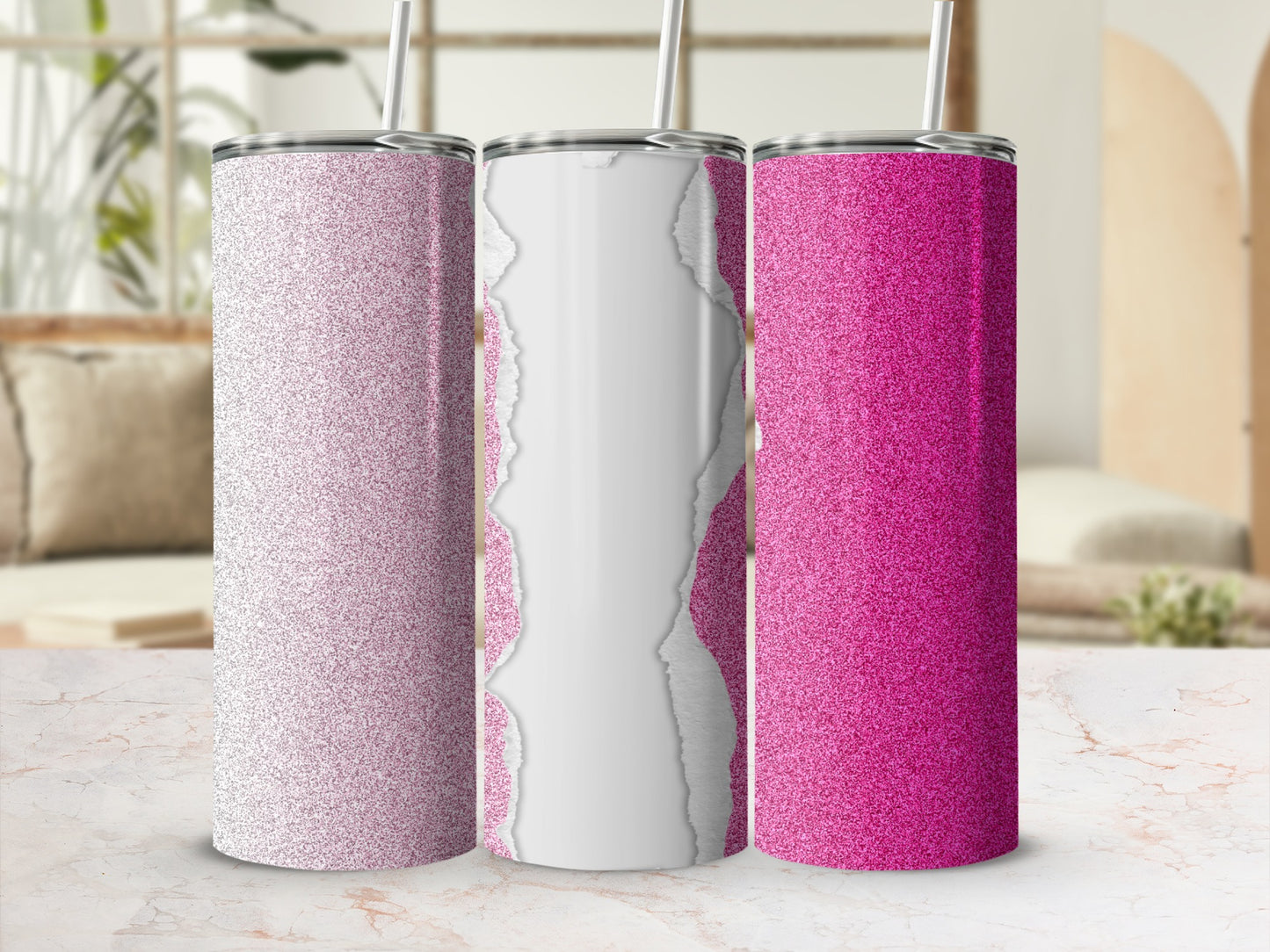 Three glitter tumblers with ripped paper effect and straws on a marbled surface.