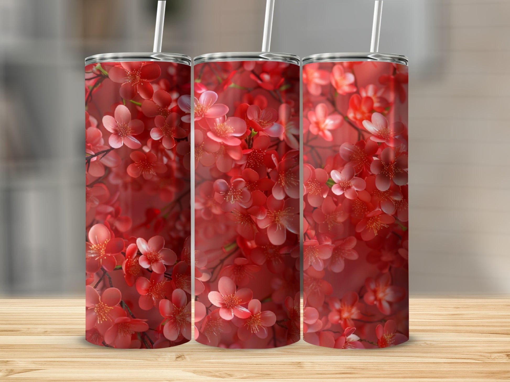 Three tumblers with a vibrant red cherry blossom pattern on a wooden surface.