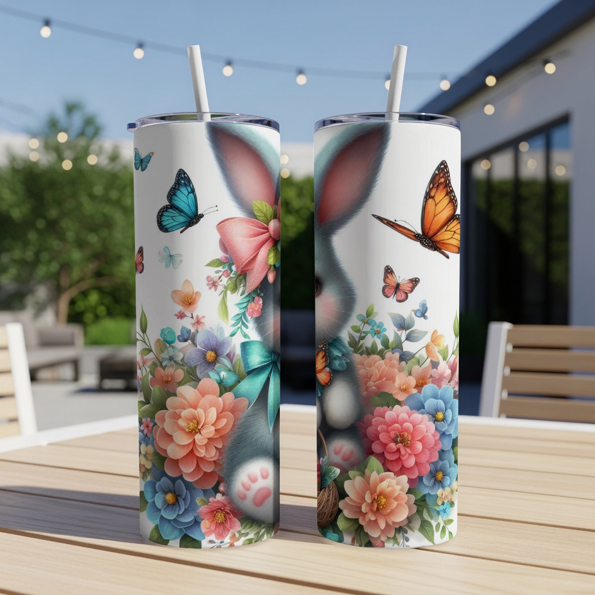 Two tumblers with Easter bunny and floral design, on a table outdoors.