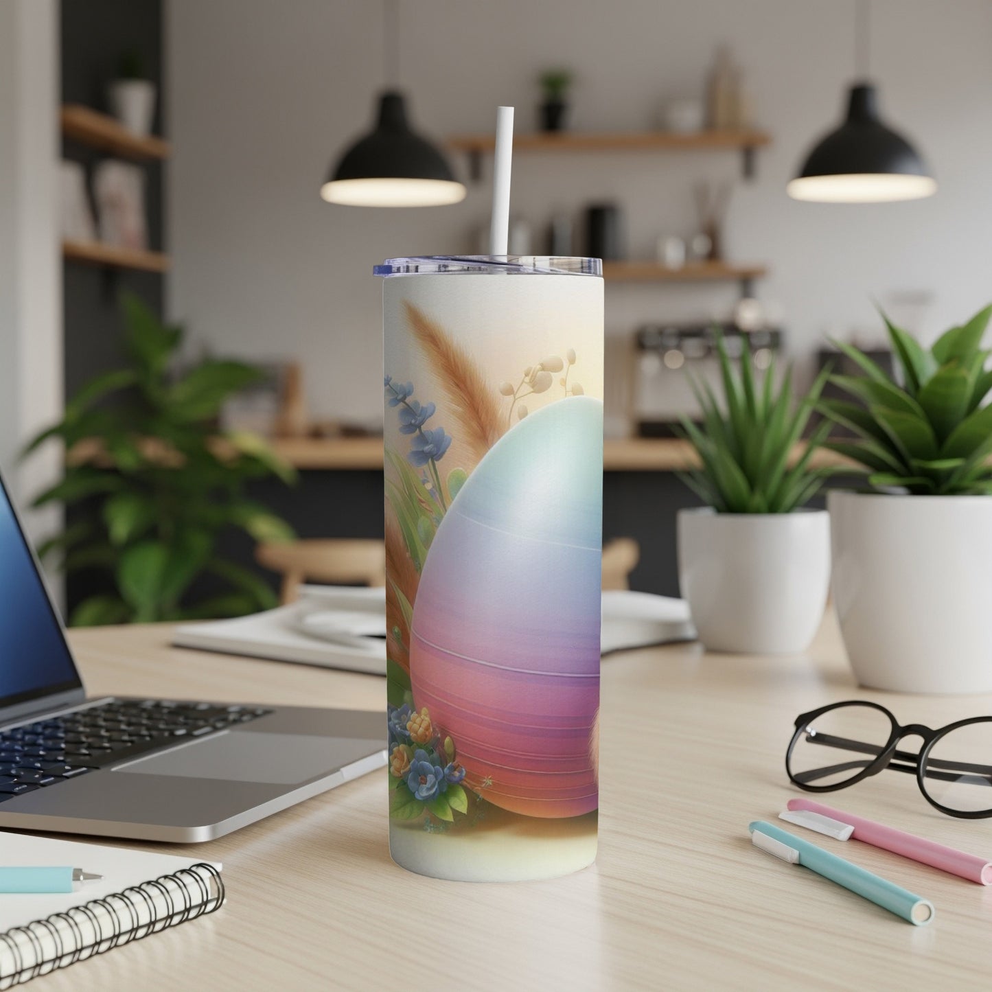 Easter egg tumbler with straw on a desk with a laptop and pens.