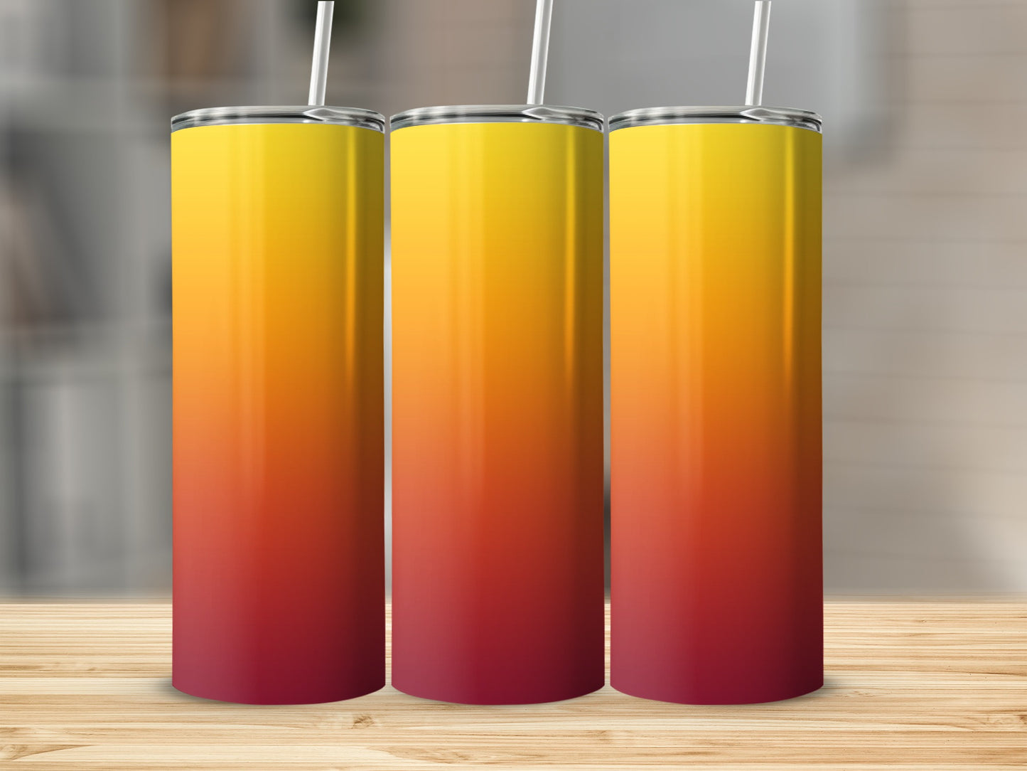 Three tall tumblers with a red to yellow gradient on a wooden surface.