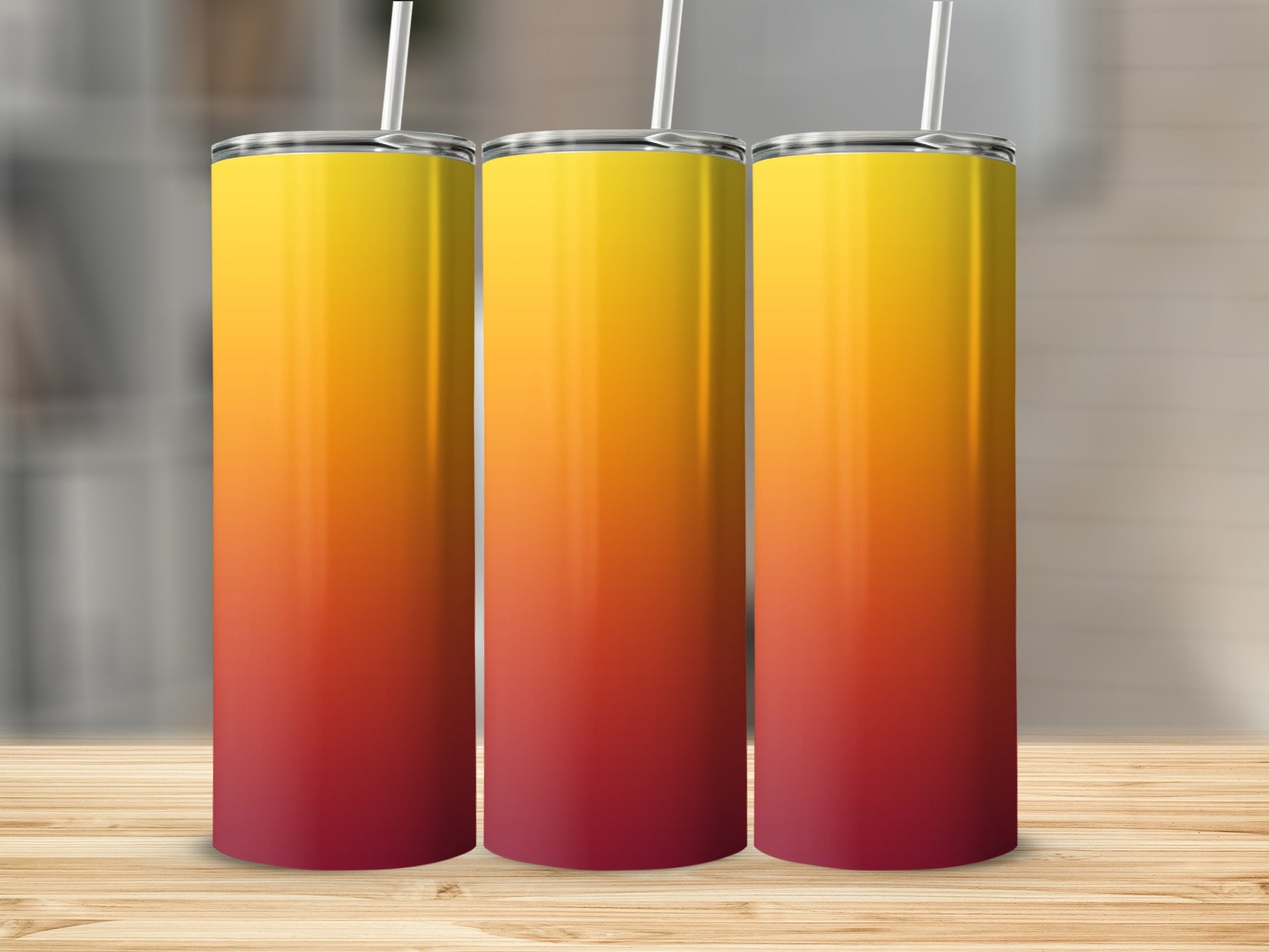 Three tall tumblers with a red to yellow gradient on a wooden surface.