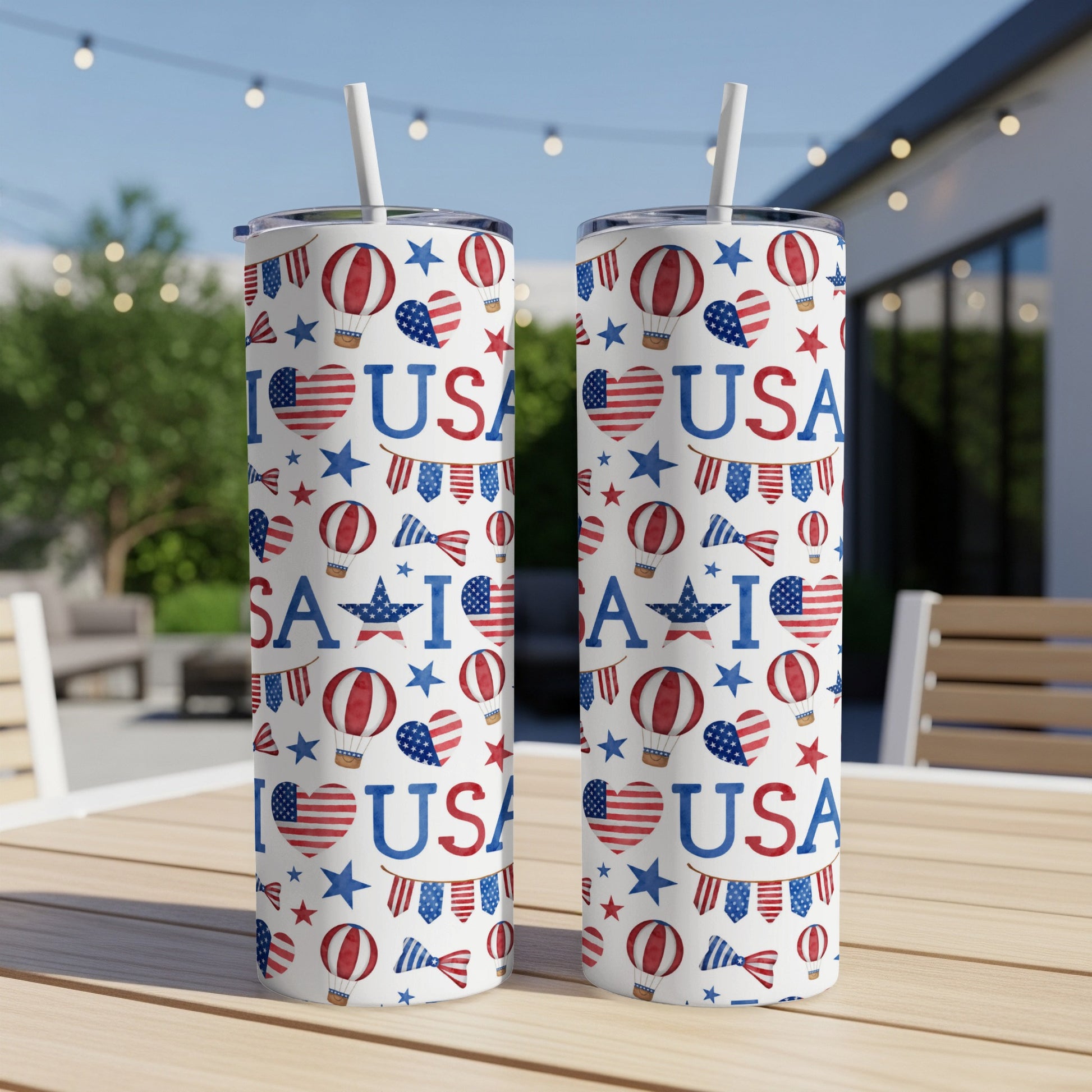 Two US flag-themed tumblers with patriotic patterns and straws on a table.