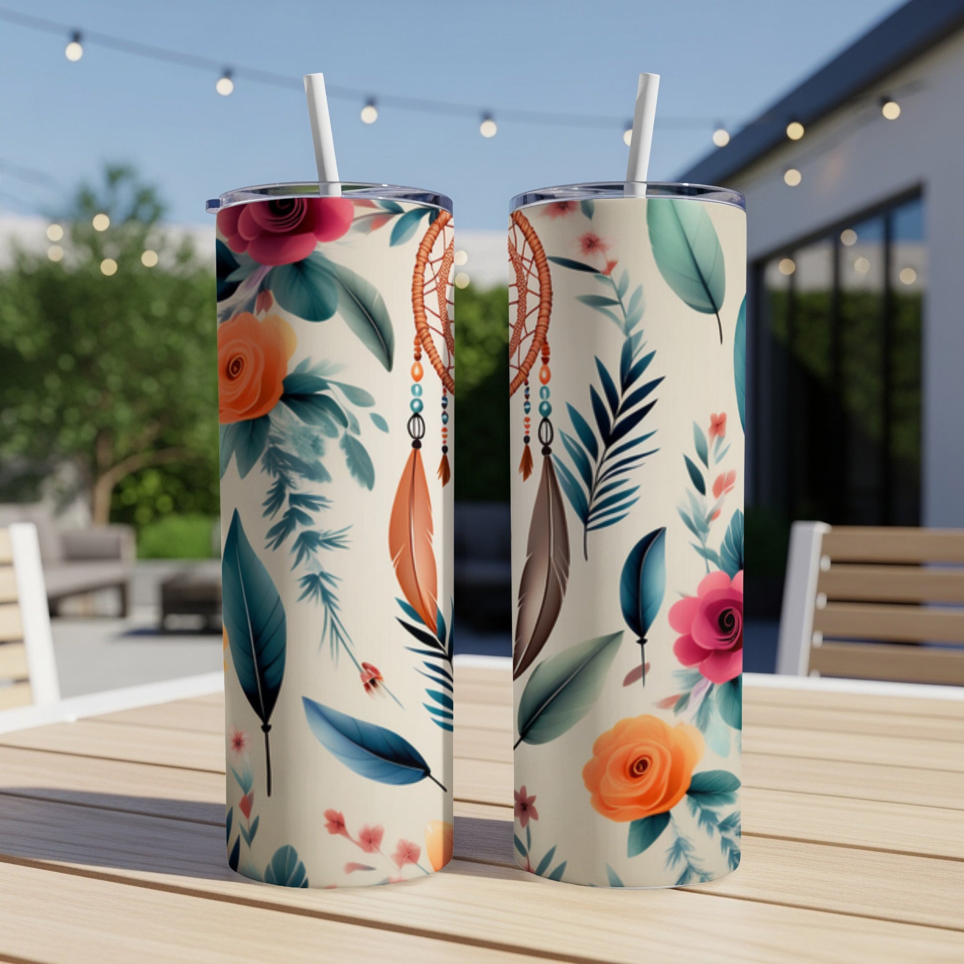 Two cream-colored tumblers with floral and feather designs on a wooden table.