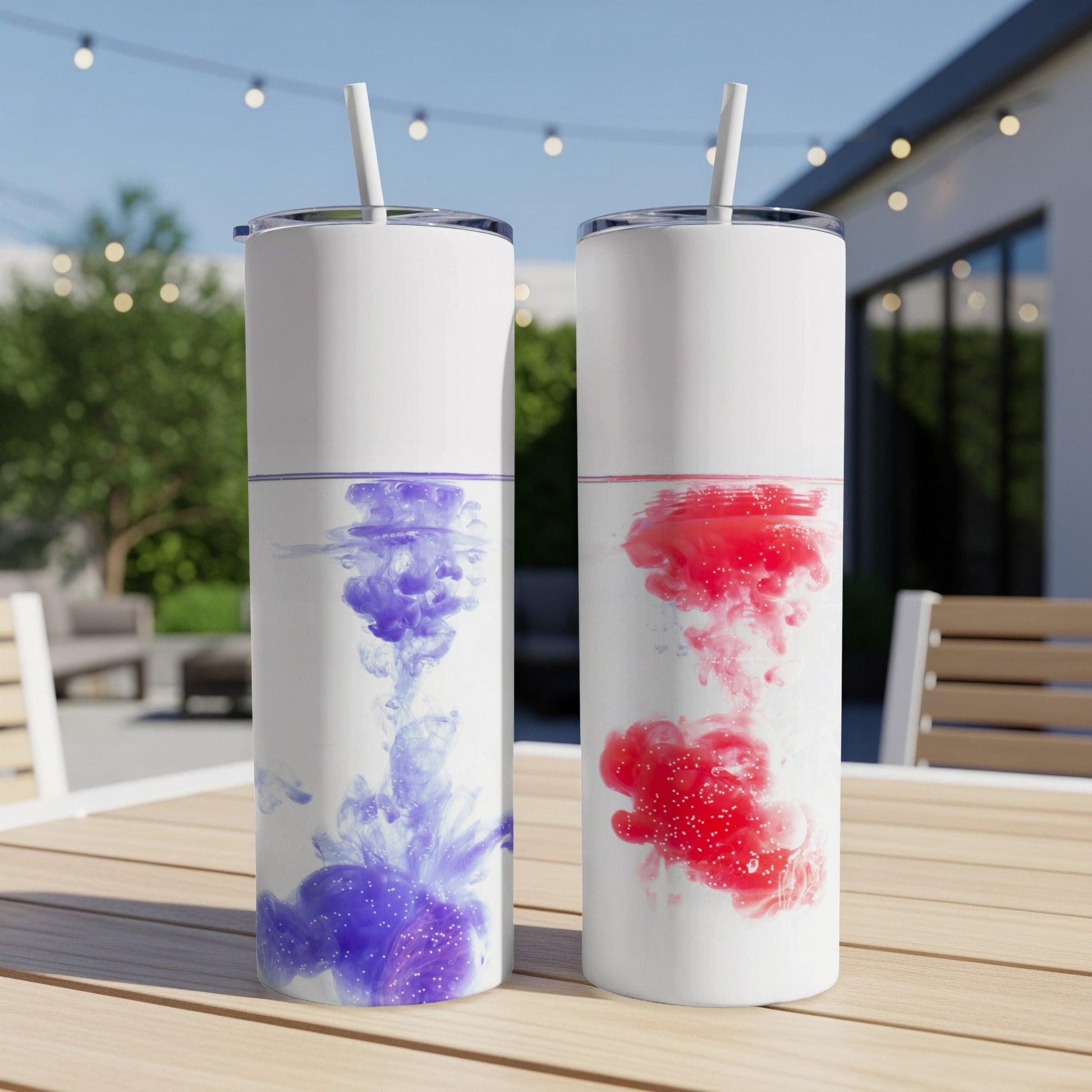 Two white tumblers with purple and red ink swirls on an outdoor table.