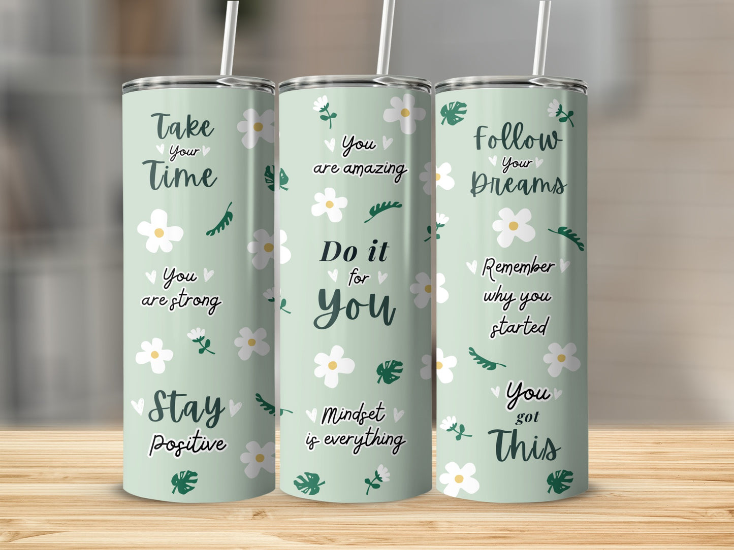 Three tumblers with motivational quotes and floral designs.