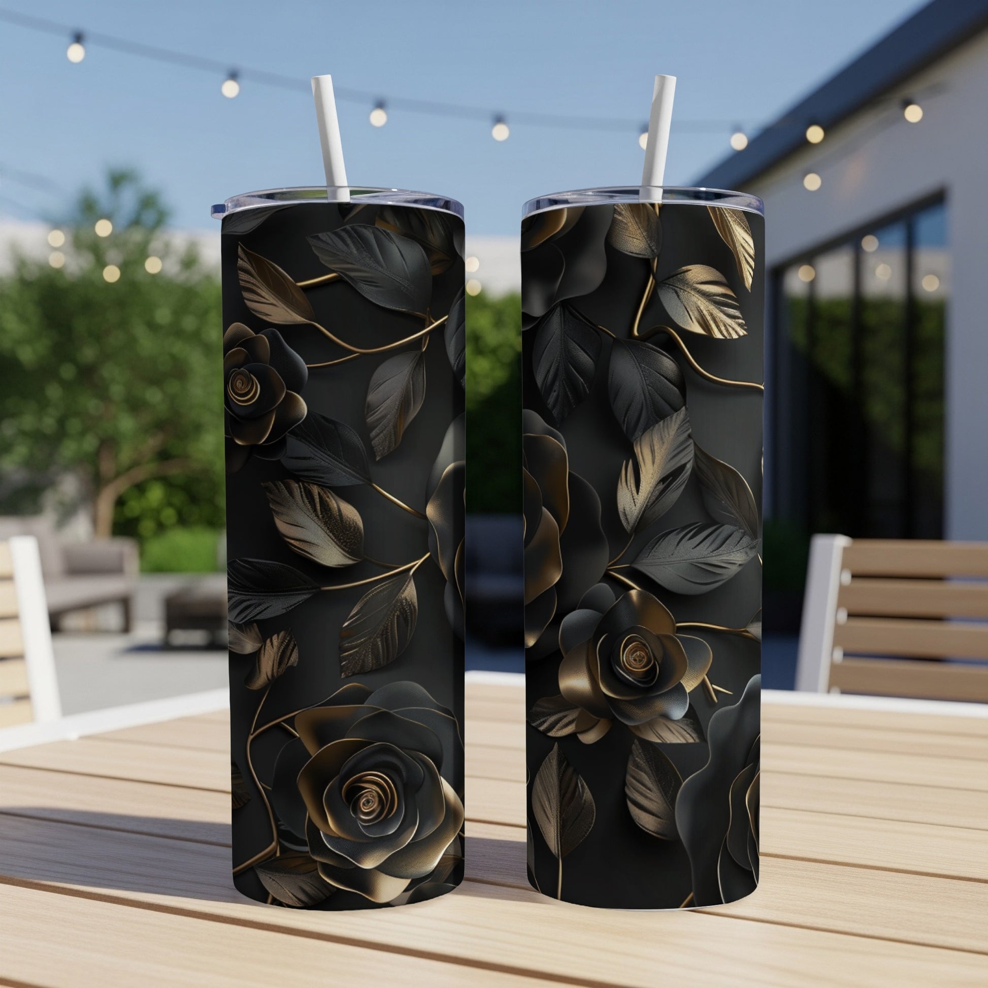 Black tumbler with gold floral design on an outdoor table.