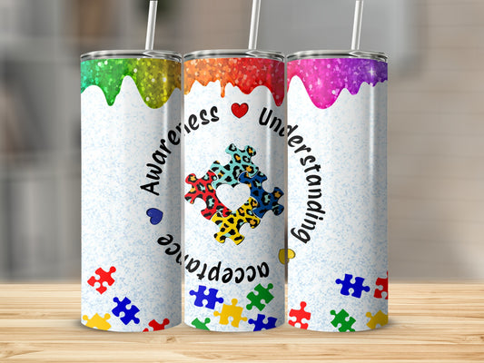 Three tumblers with colorful autism awareness puzzle piece designs.