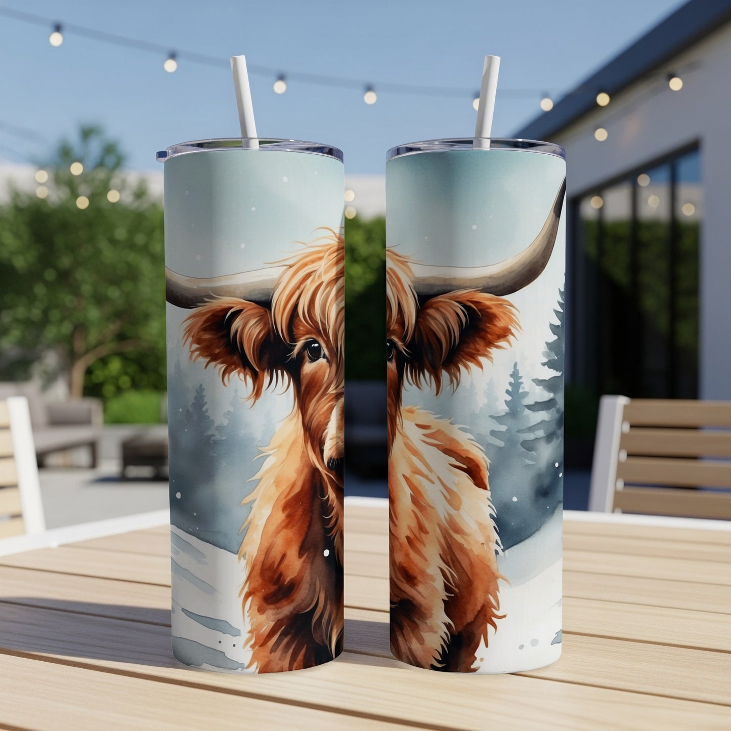 Highland cow illustration on a white tumbler with a straw, set outdoors.