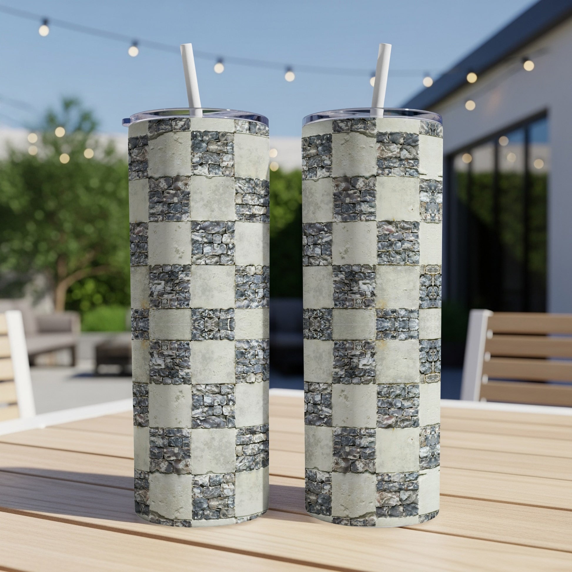 Two stainless steel tumblers with a stone tile checkered pattern sit on a table.