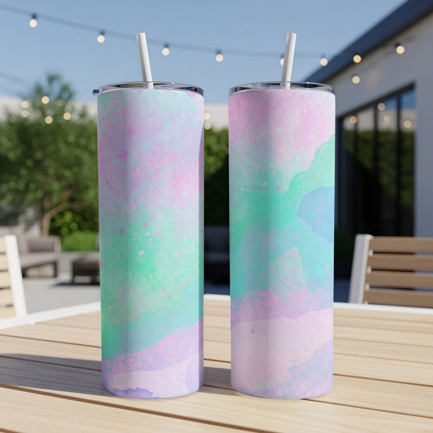 Two tall tumblers with pastel pink, purple, and teal marbled patterns on a wooden table.