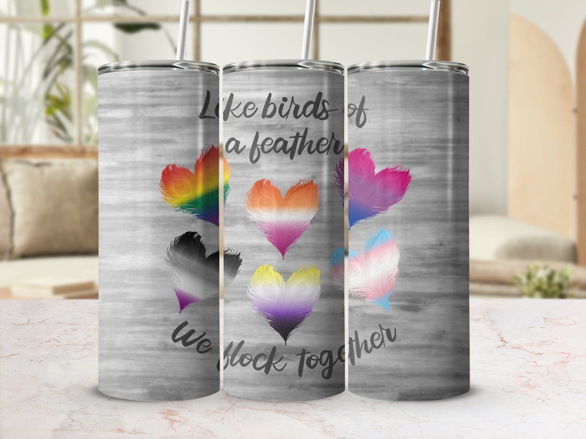 Tumbler with rainbow, non-binary, and trans pride heart feathers and text.