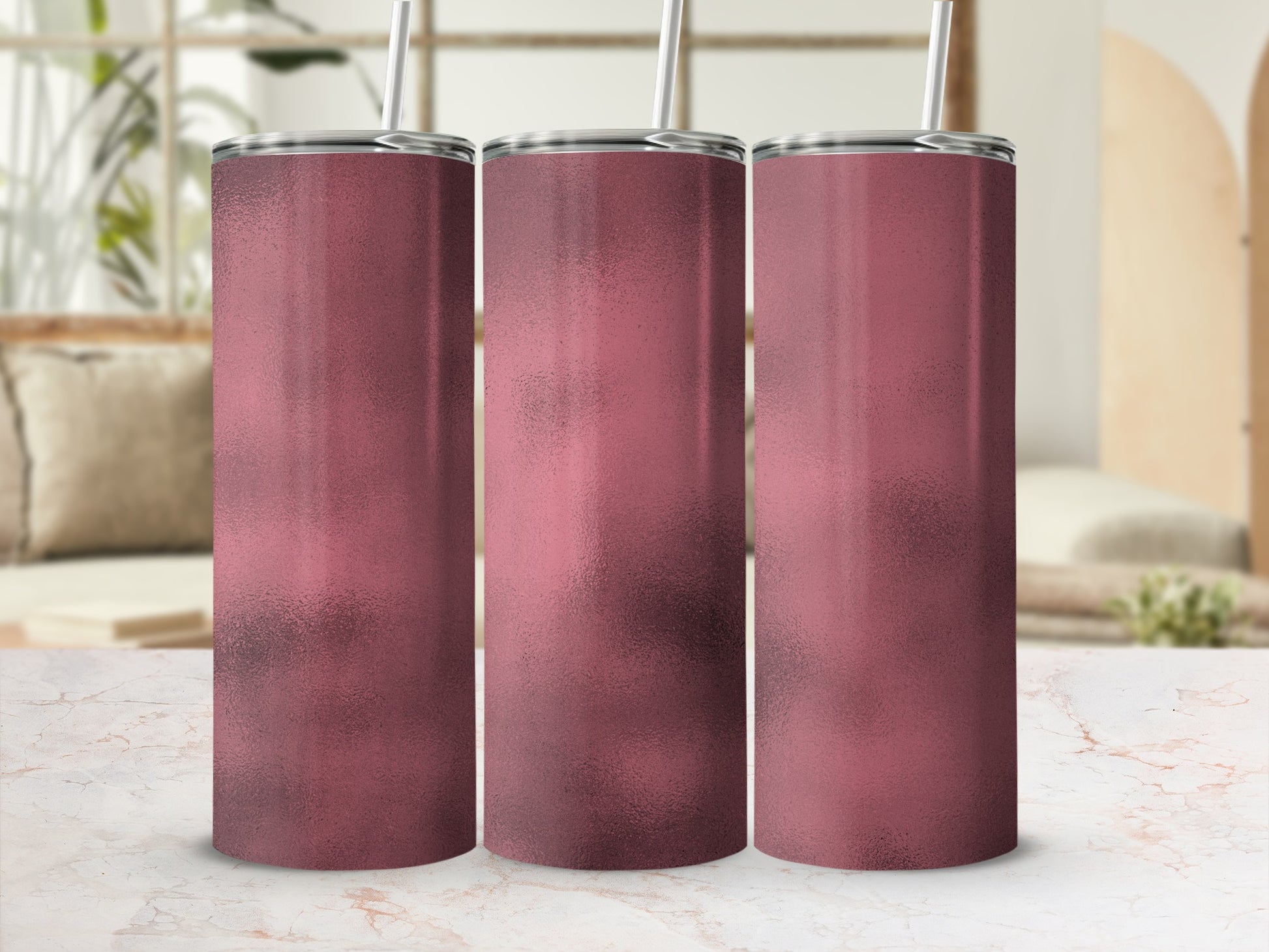Three rose gold metallic tumblers with silver straws displayed in a studio setting.