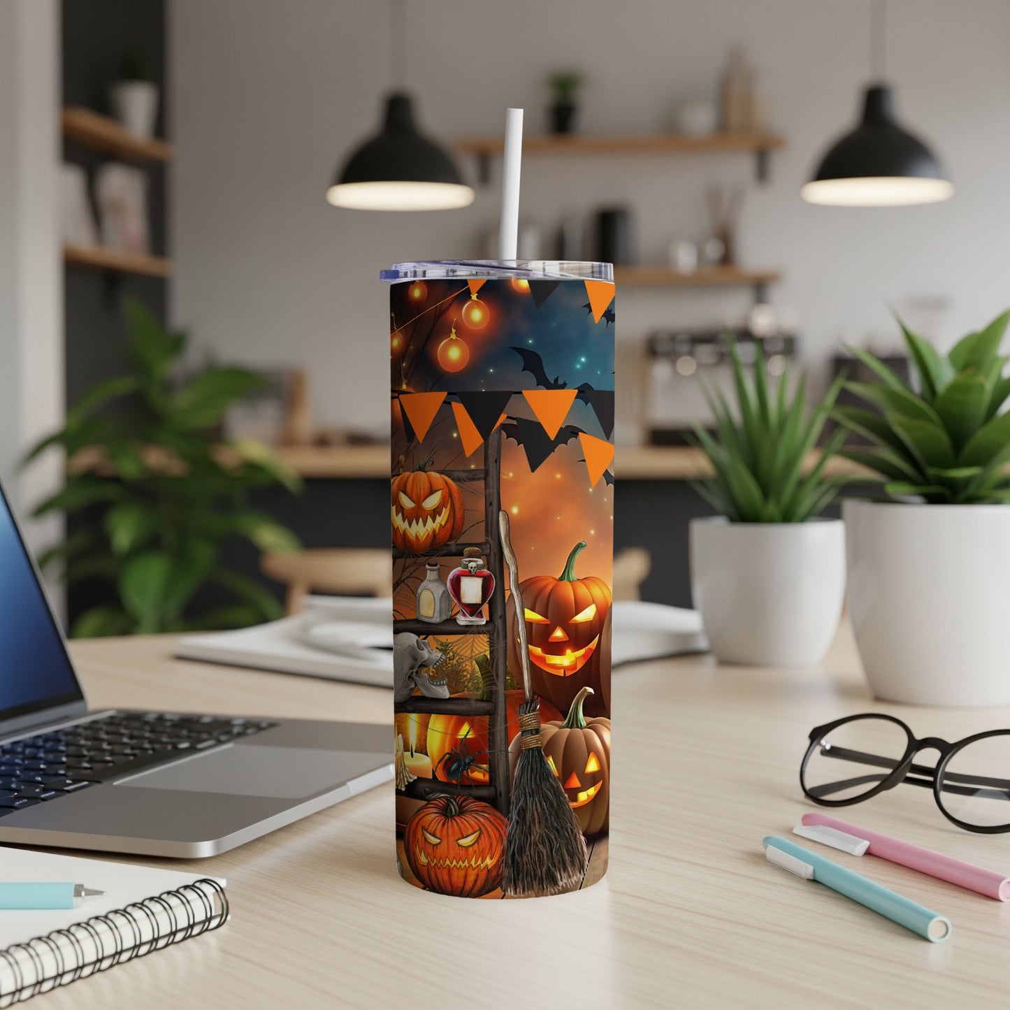 Halloween tumbler with jack-o'-lanterns, bats, and spooky decorations on a wooden desk.