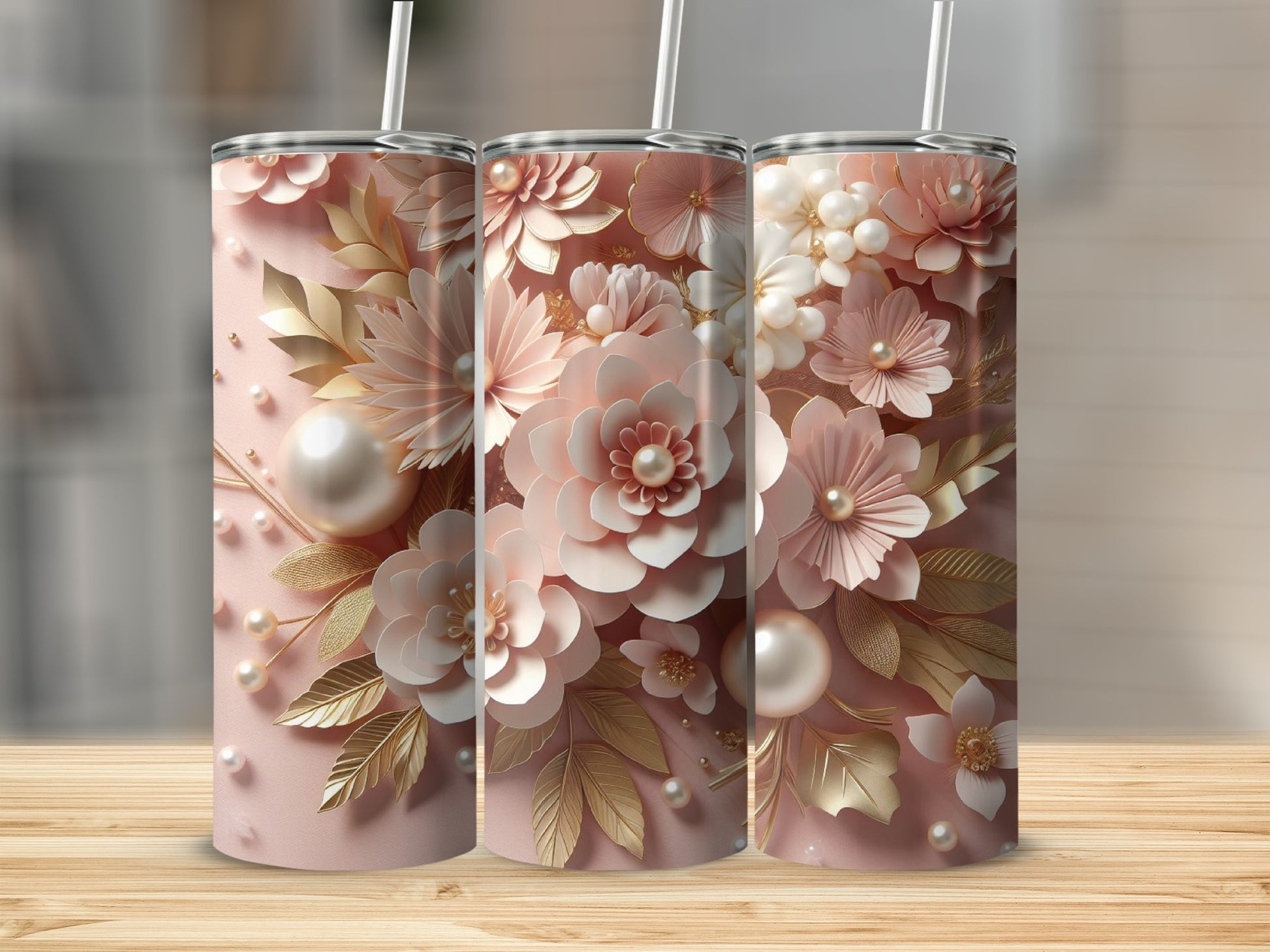 Three pink tumblers with floral and pearl embellishments on a wooden surface.