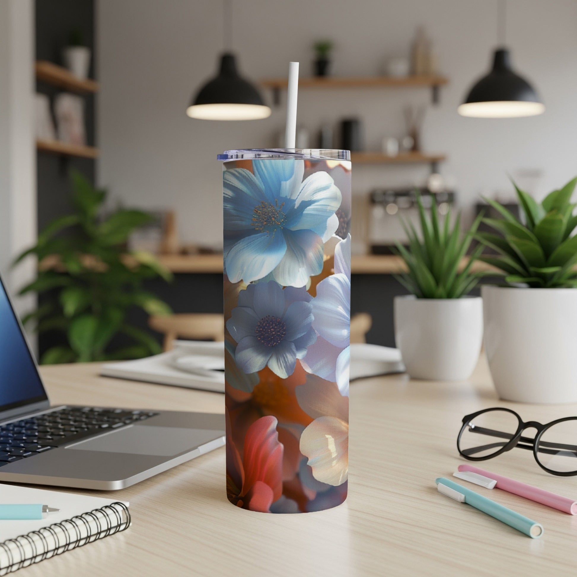 Floral pattern tumbler with straw on a wooden desk with a laptop.