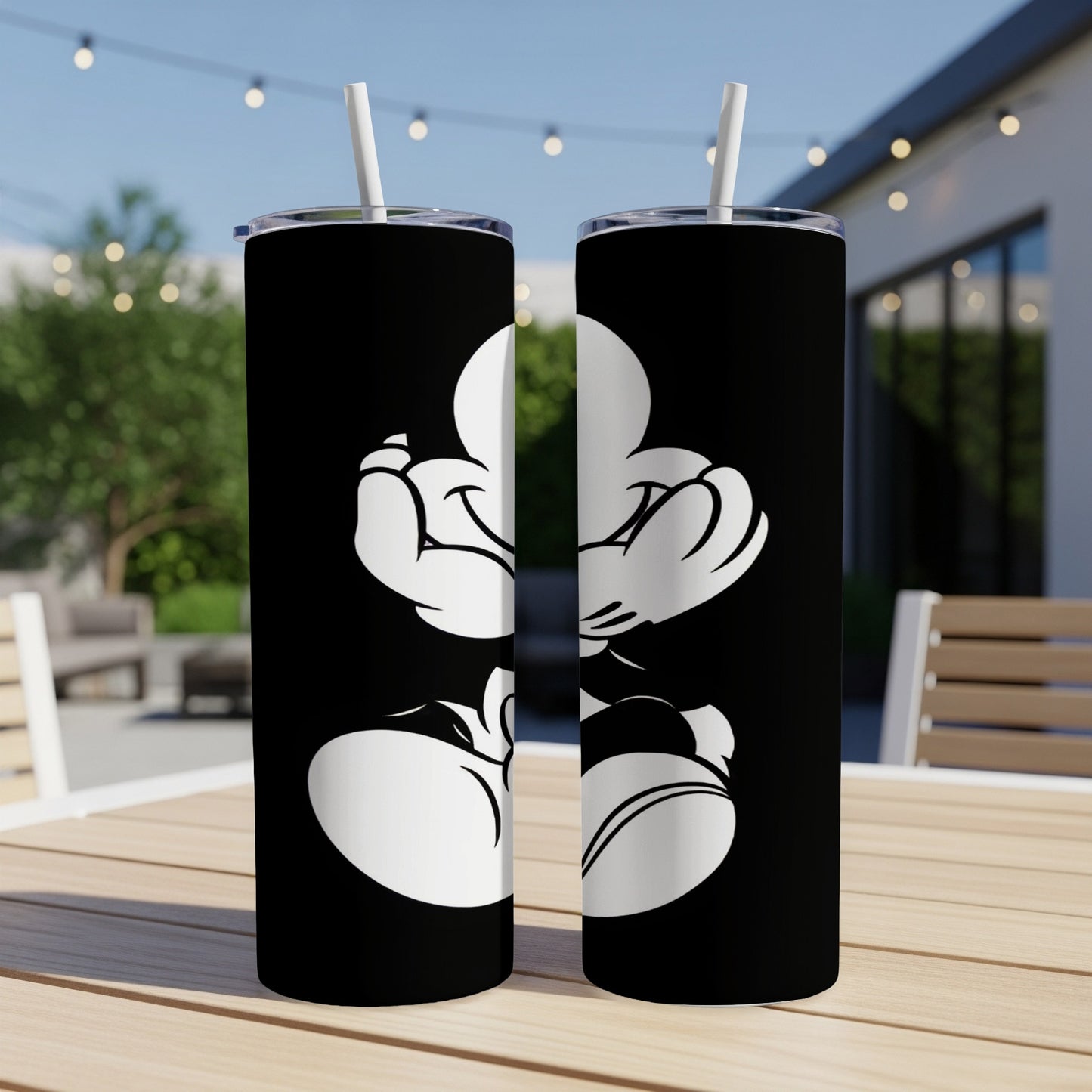 Black tumbler with white Mickey Mouse silhouette on a patio table.