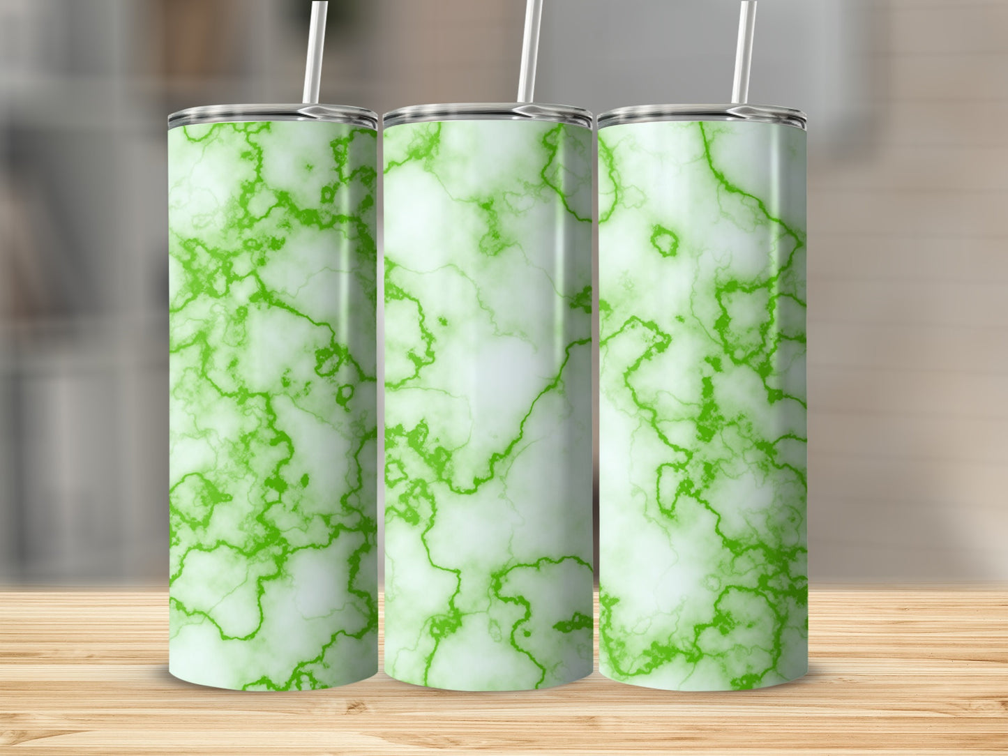 Three green marble pattern tumblers with straws on a wooden surface.
