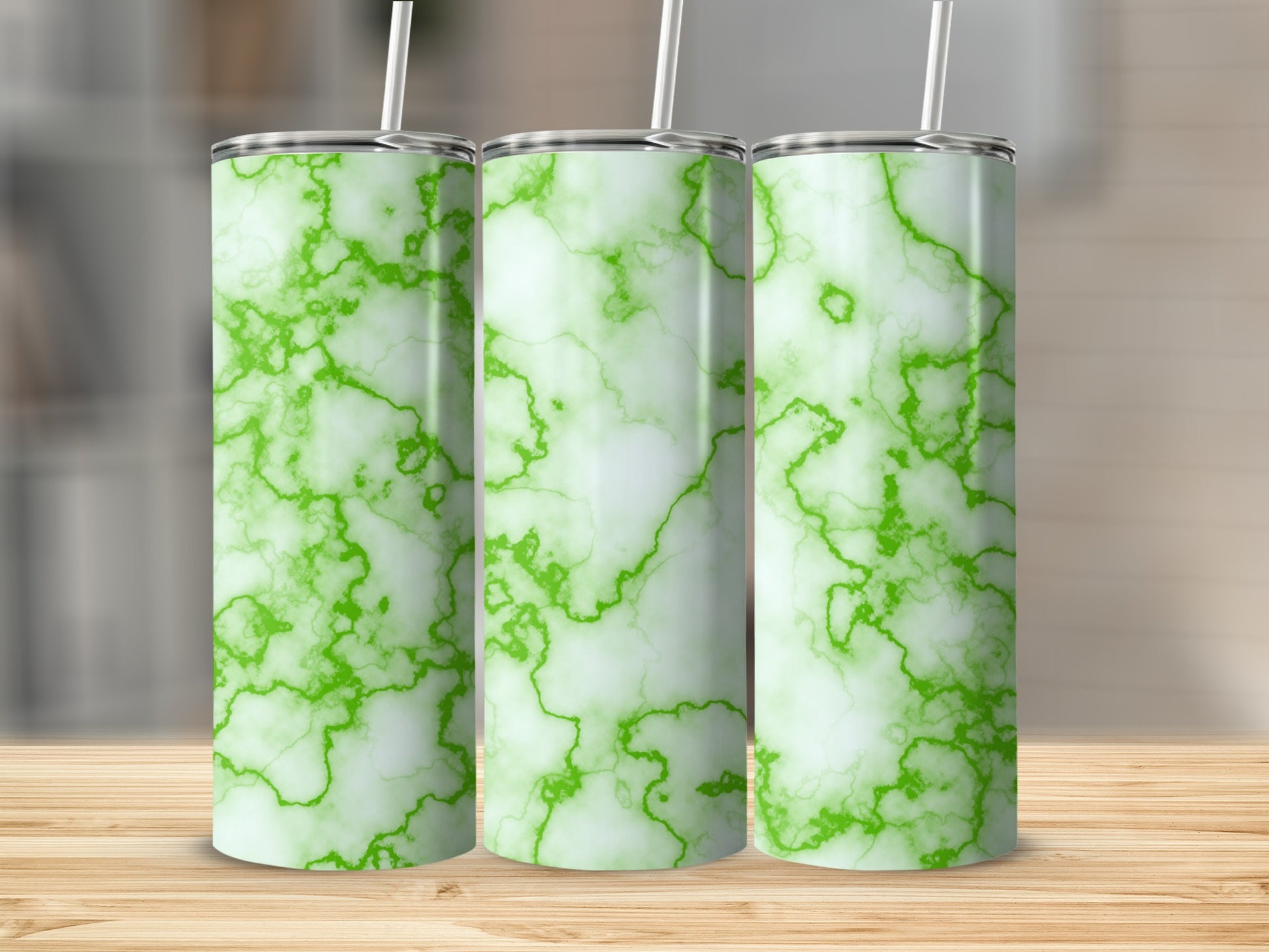 Three green marble pattern tumblers with straws on a wooden surface.