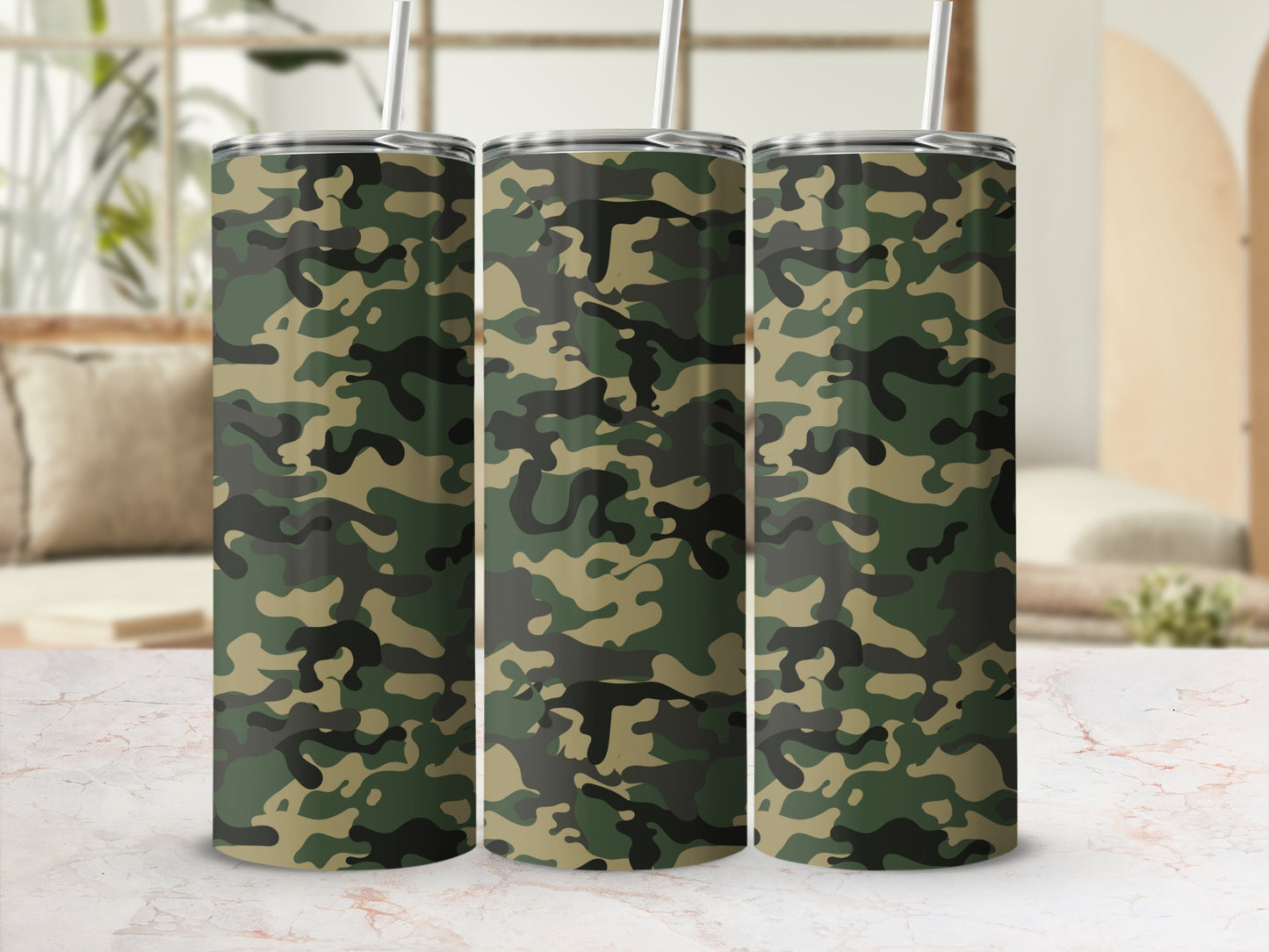 Three tumblers with camouflage pattern and metal straws on a marble surface.