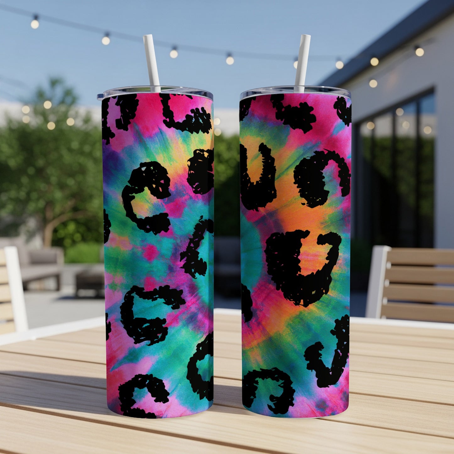 Two tie-dye tumblers with black leopard print accents stand on a table.