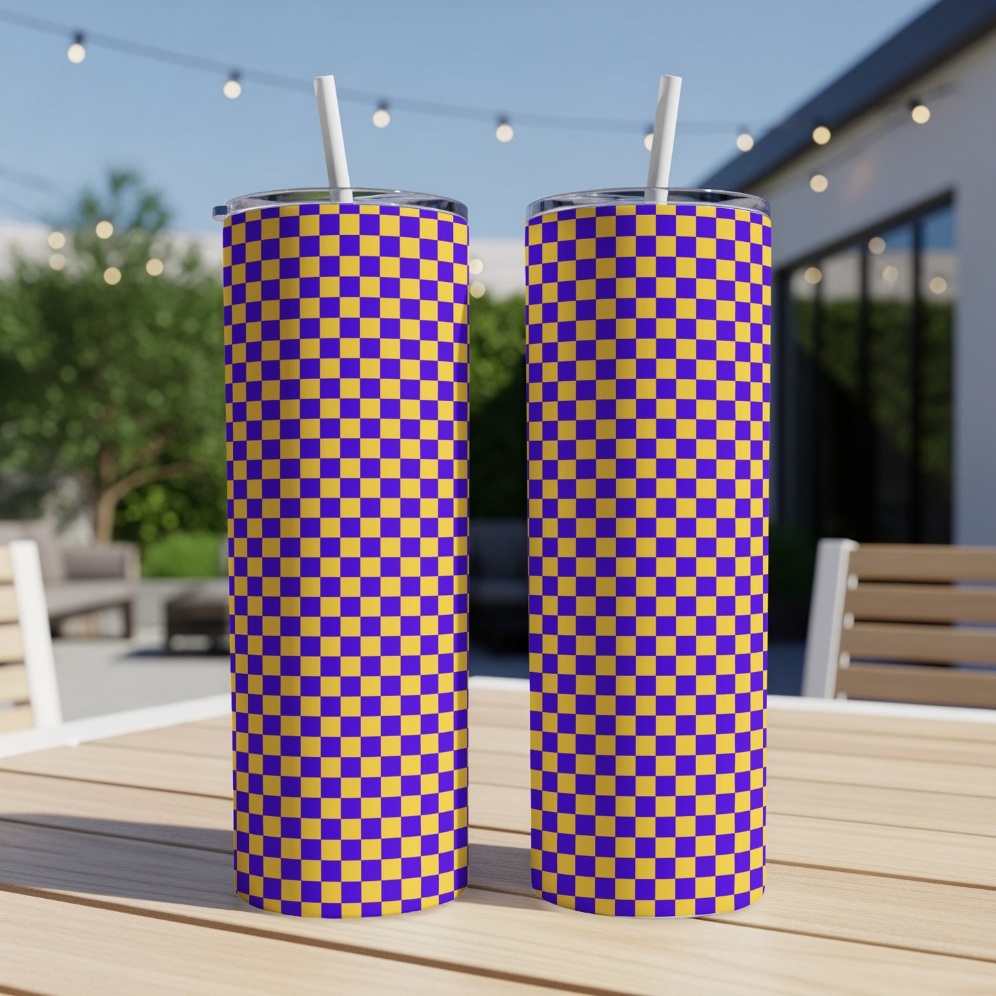 Two purple and yellow checkered tumblers with straws on a wooden table.