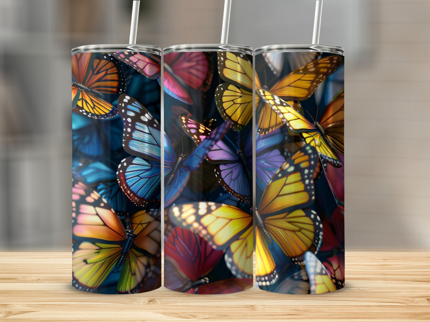 Three tumblers with colorful butterfly designs, shown on a wooden surface.