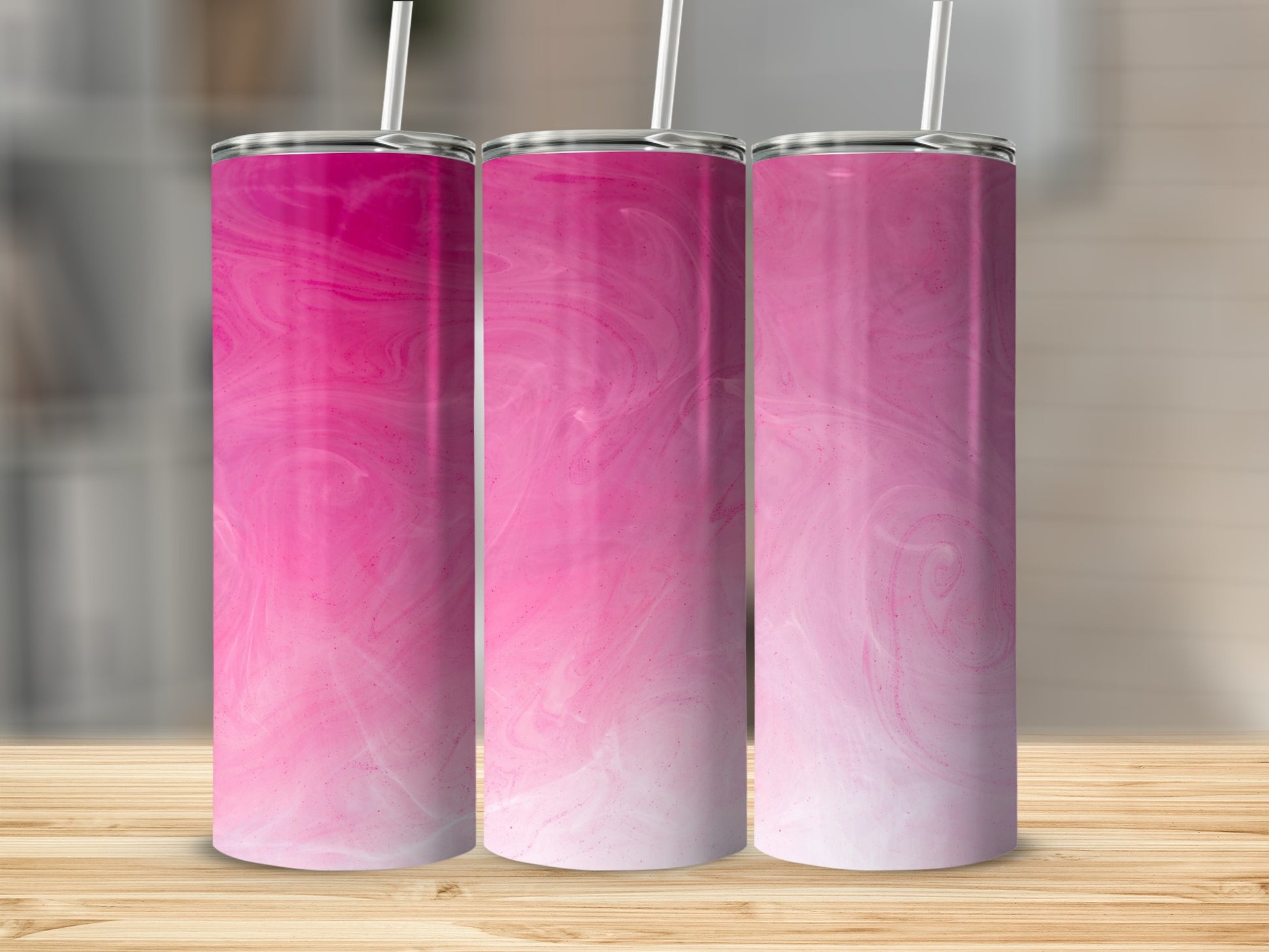 Three pink and white marbled tumblers with straws on a wooden surface.