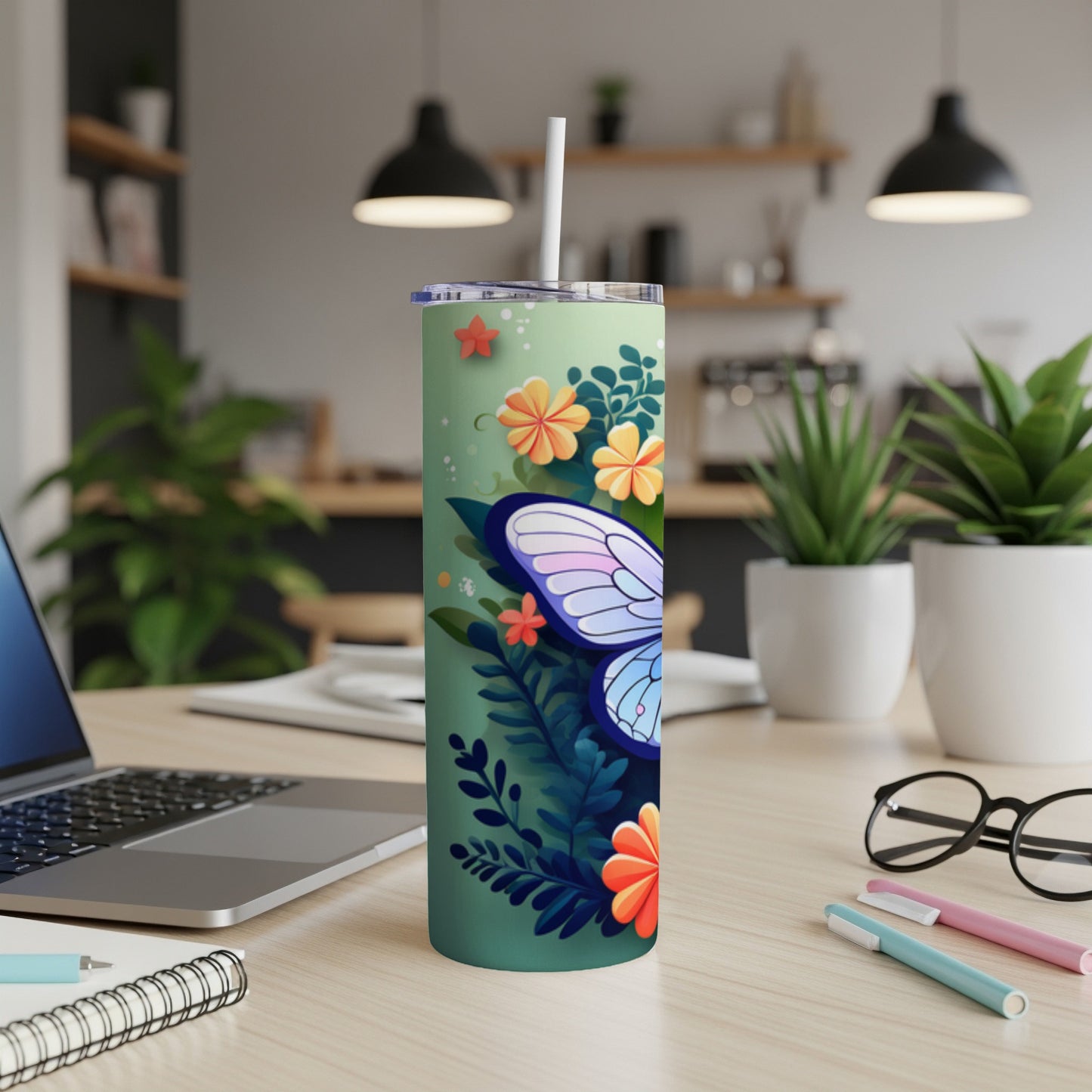 Floral tumbler with butterfly and straw on a desk.