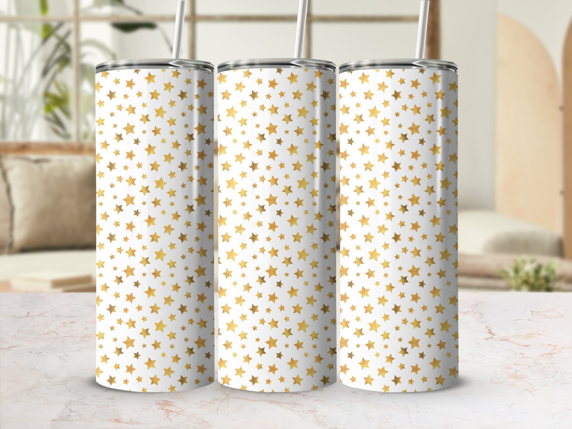 Three tumblers with a white background and scattered gold star pattern, each with a straw.