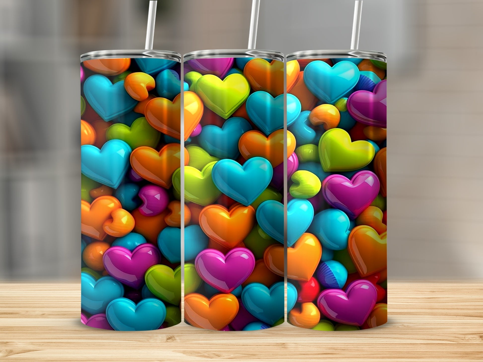 Three colorful tumblers with heart designs stand on a wooden surface.