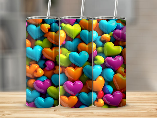 Three colorful tumblers with heart designs stand on a wooden surface.