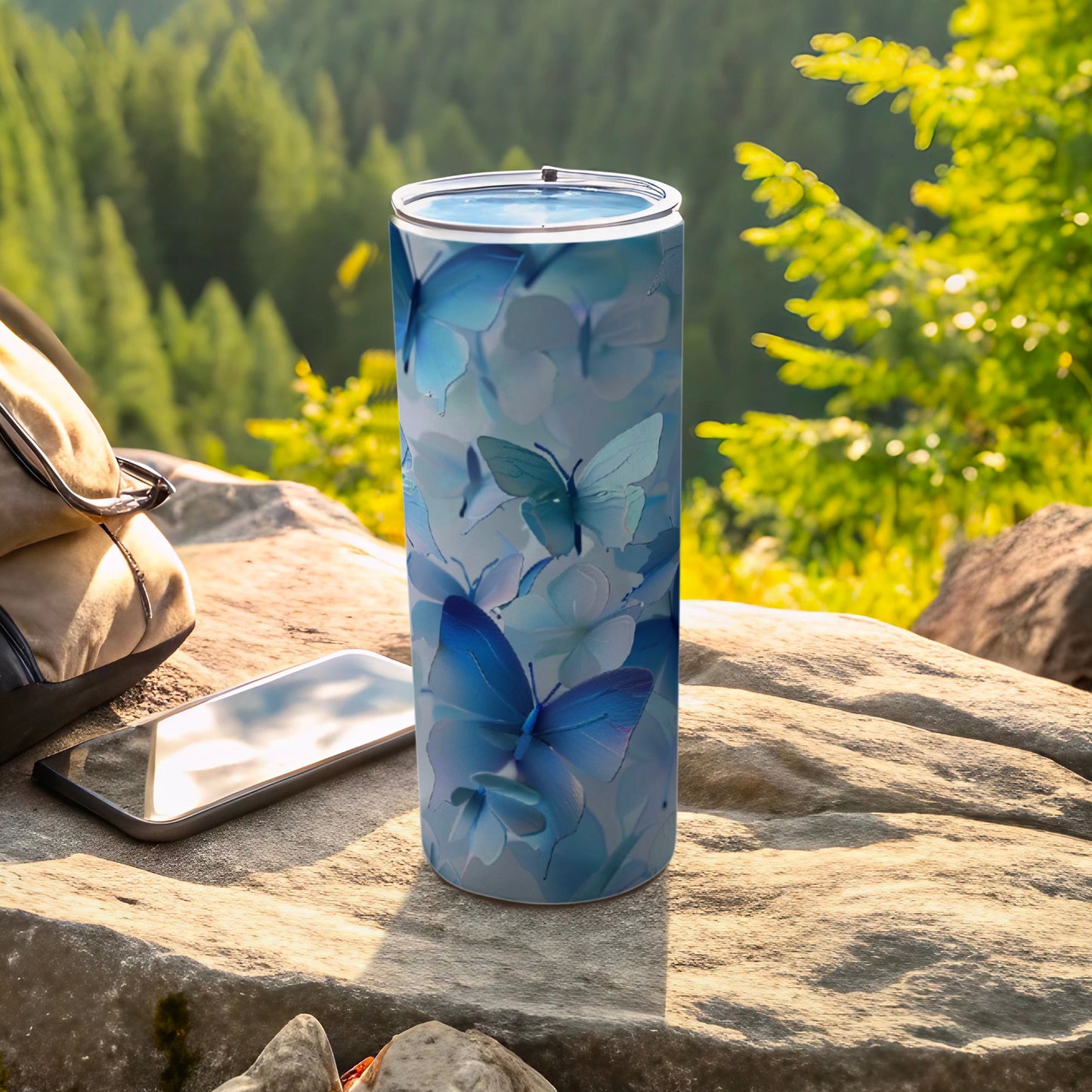 Blue butterfly pattern on a stainless steel tumbler with a smartphone and backpack.