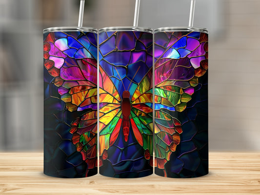 Three stained glass butterfly tumblers with colorful iridescent wings on a wooden surface.