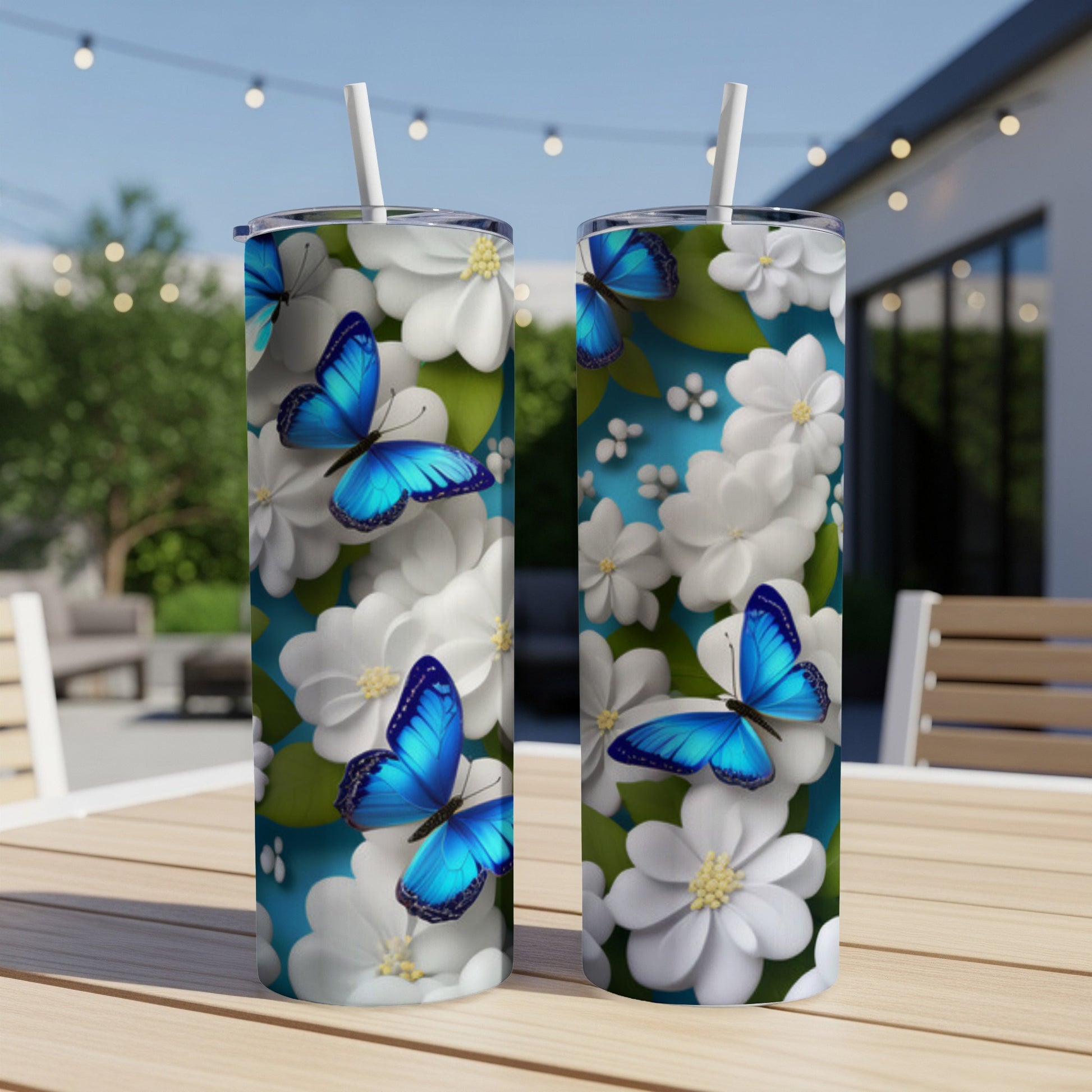 Two tall tumblers with blue butterflies and white flowers on a table.