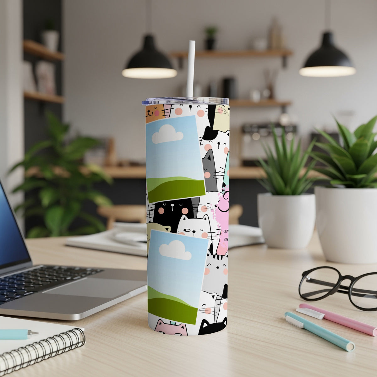Tumbler with a collage of cartoon cats and two photo frames on a desk.