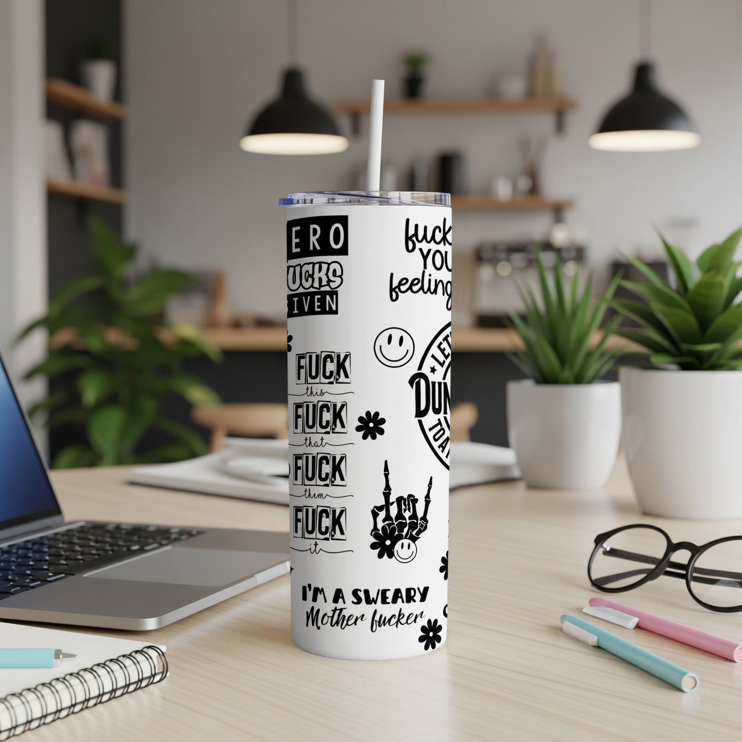 Tumbler with "f*ck you feeling" and other phrases, on a desk.