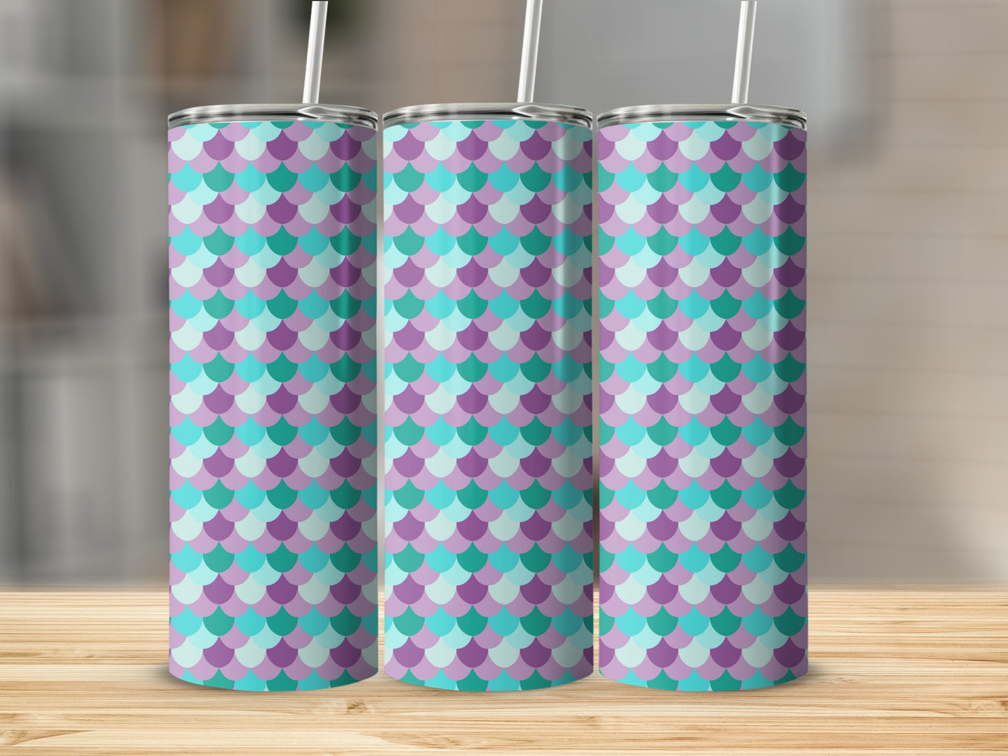 Three tumblers with a purple and teal mermaid scale pattern stand on a wooden surface.