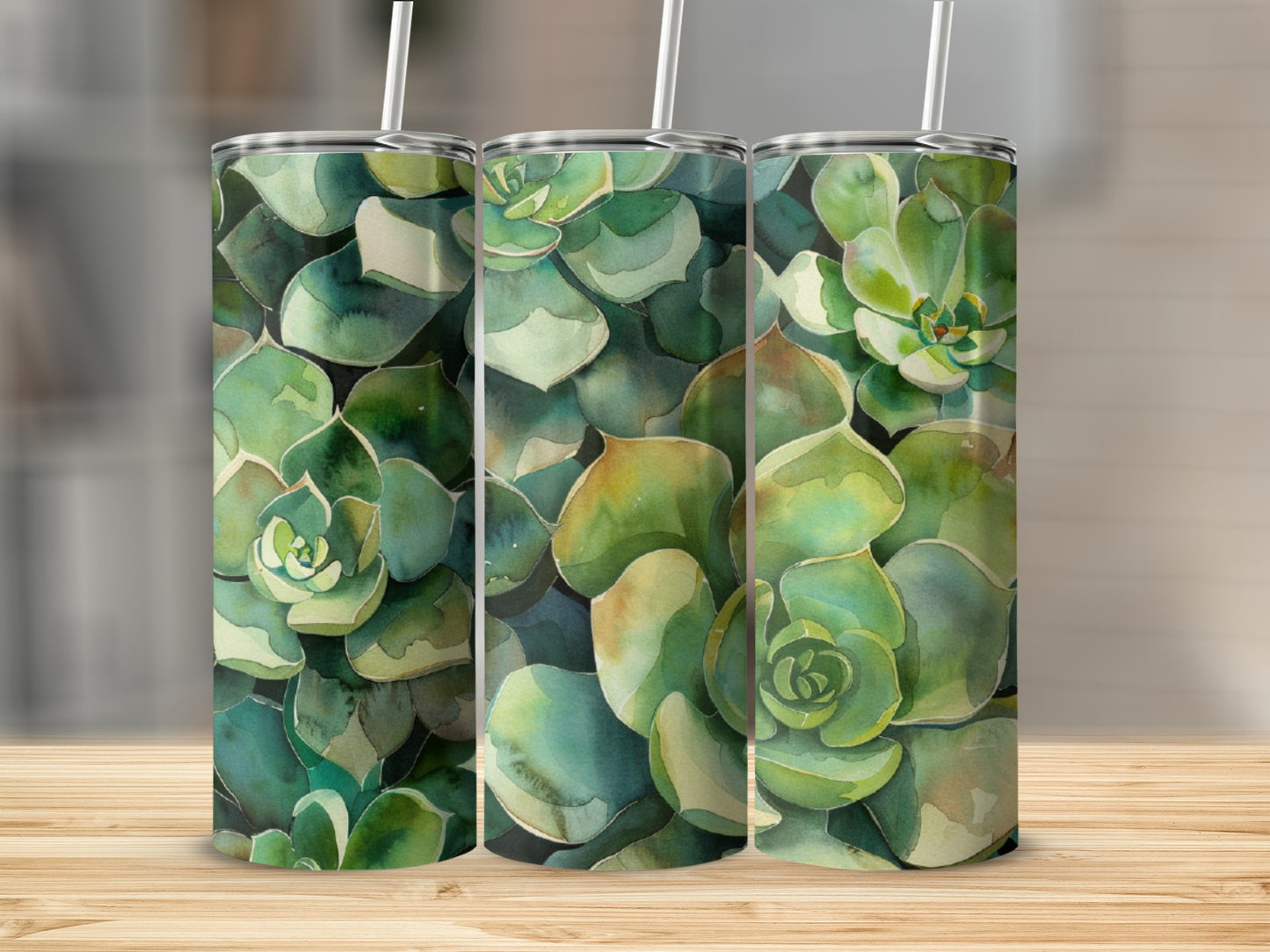 Three tumblers with a watercolor succulent pattern sit on a wooden surface.