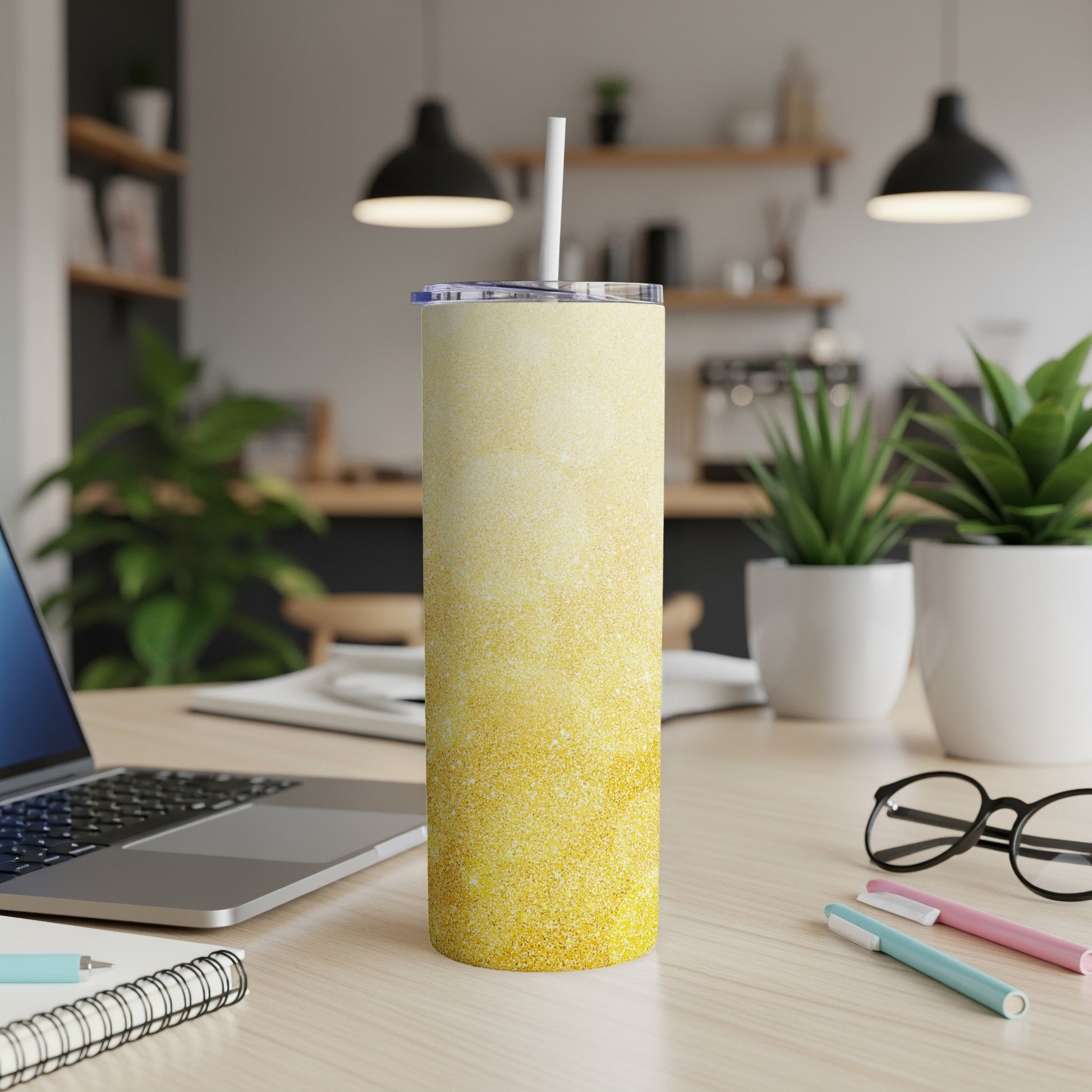 Yellow glitter ombre skinny tumbler with white straw on wooden desk.