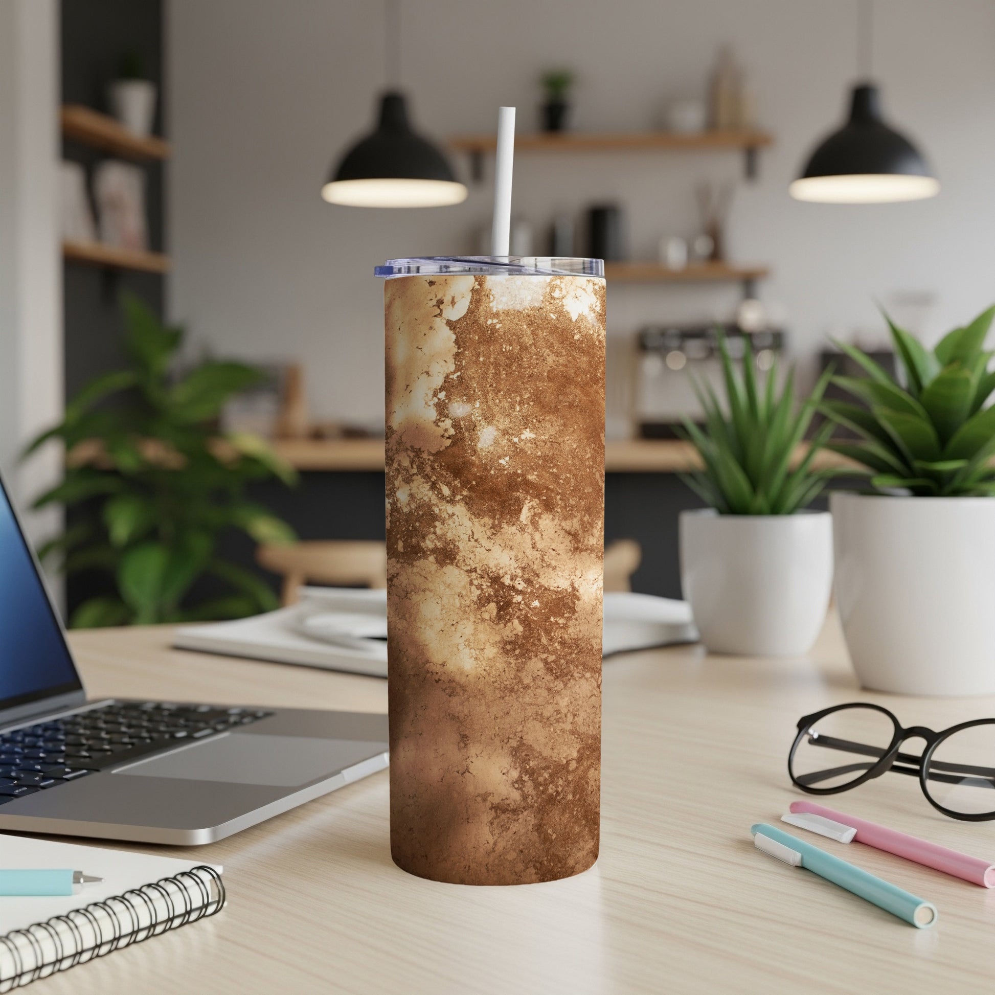 Brown and beige marbled tumbler with straw on desk.