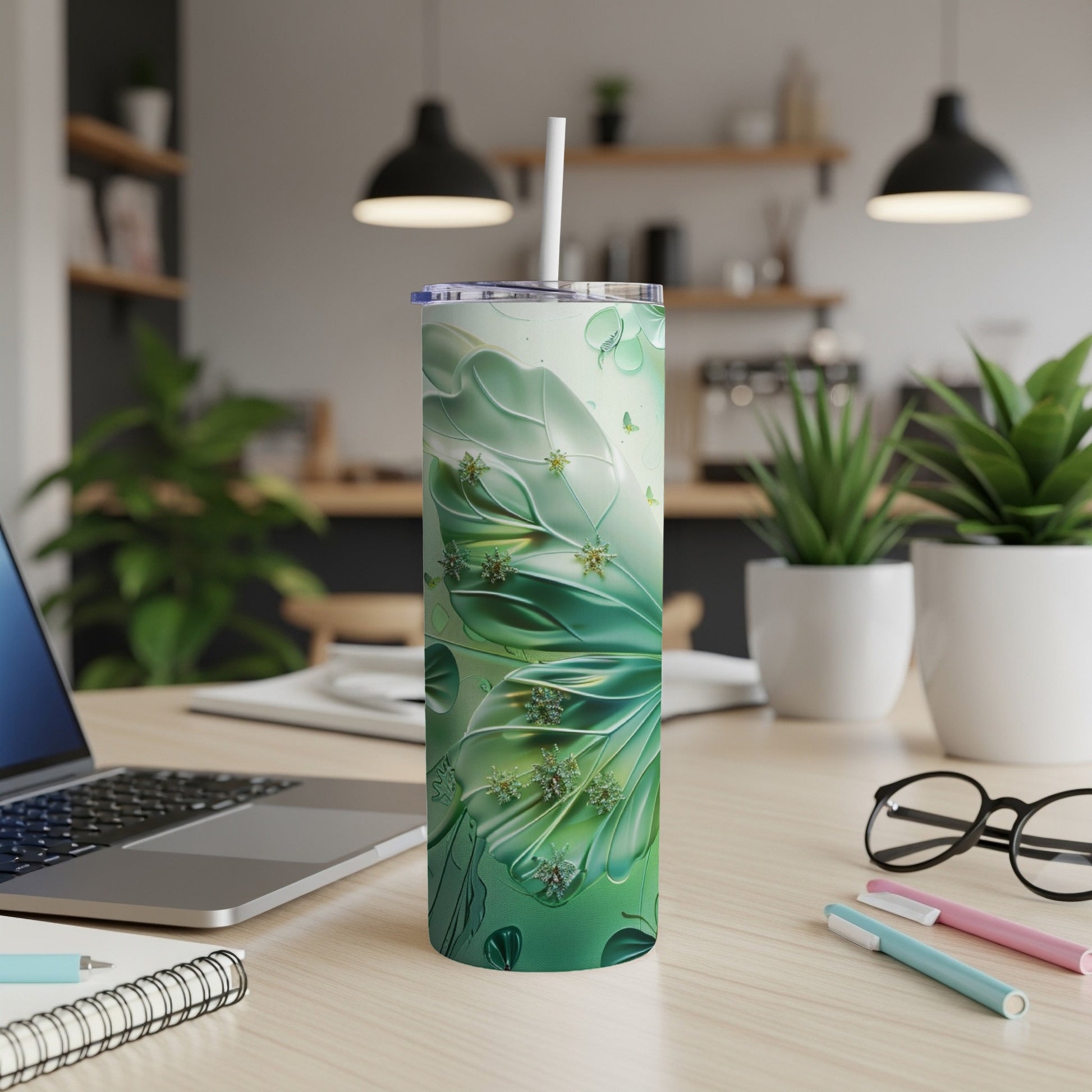 Green butterfly wing patterned tumbler with straw on desk.